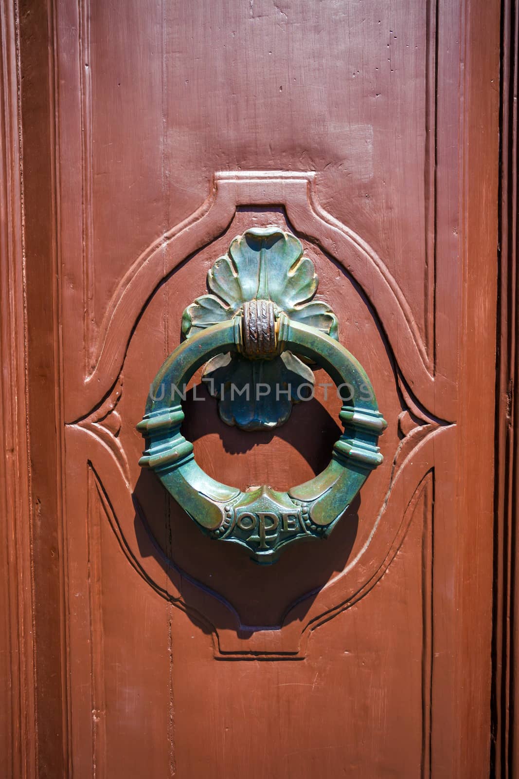 Traditional knocker shaped metal on a brown door, Pisa, Italy