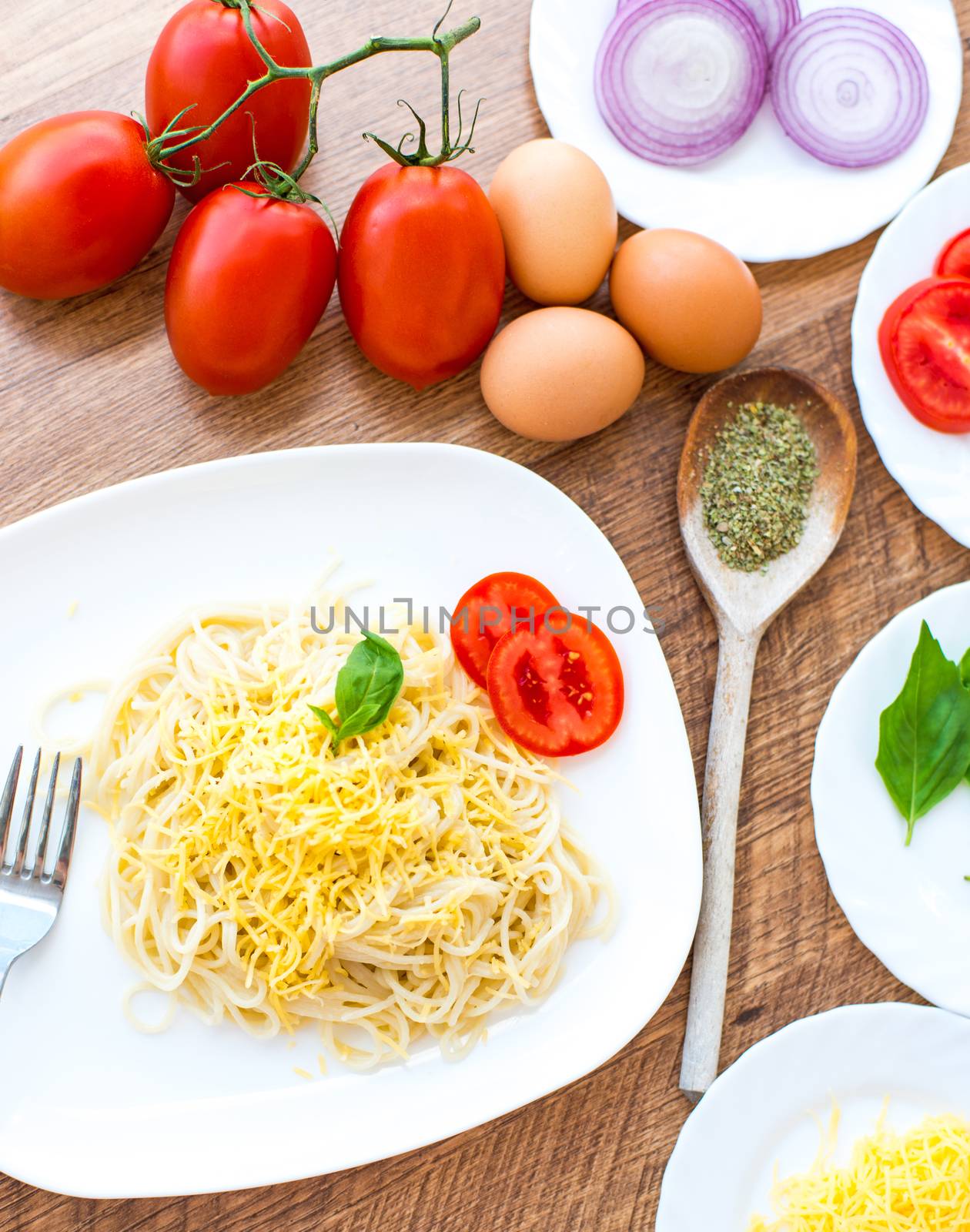 spaghetti dinner with tomatoes, cheese and basil close up