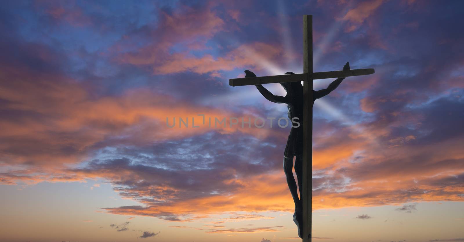 Jesus Christ on the Cross with sunset clouds as a background