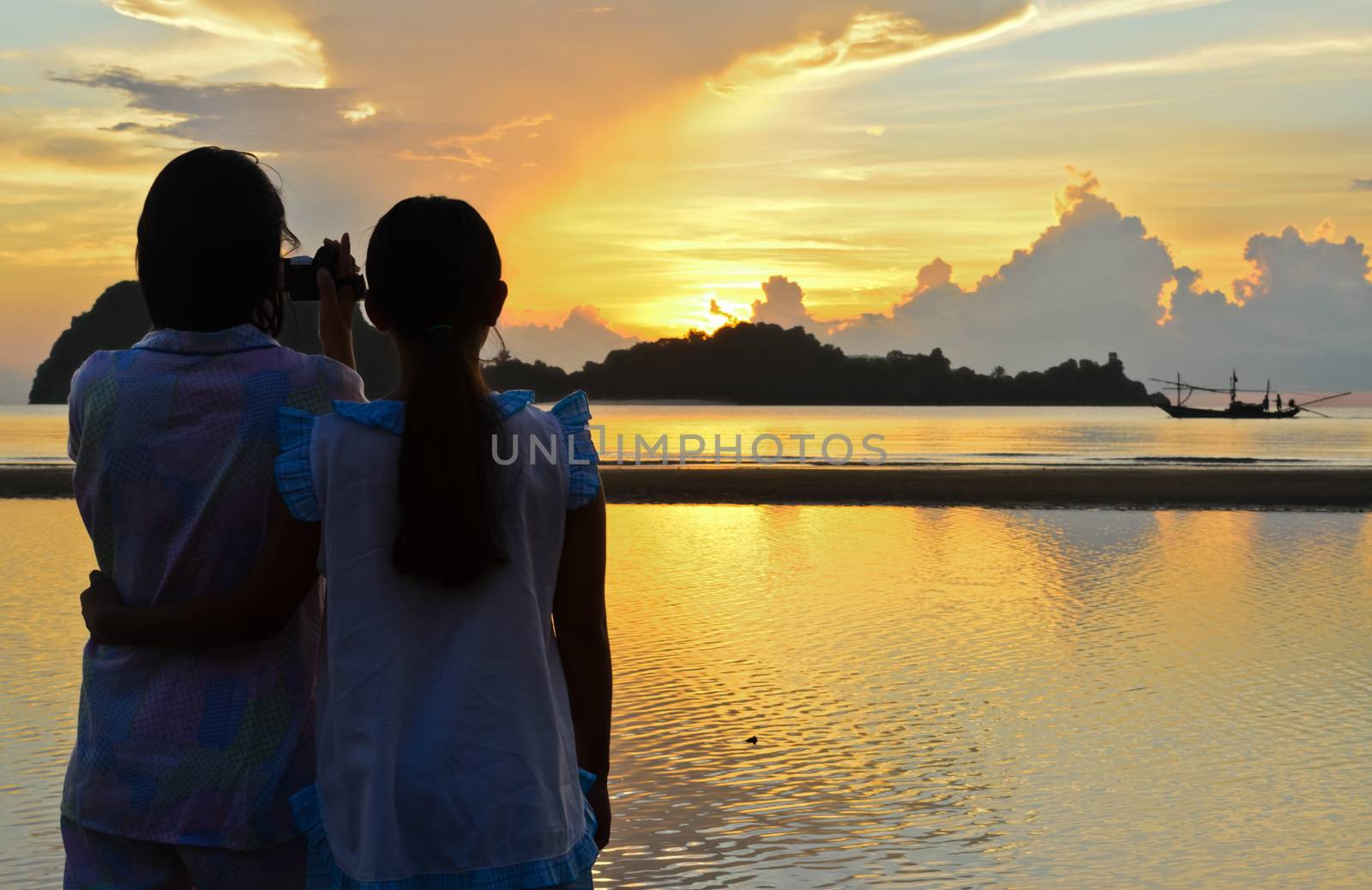 Mother and daughter are very happy to video recording the sunrise on the beach in Chumphon Province of Thailand