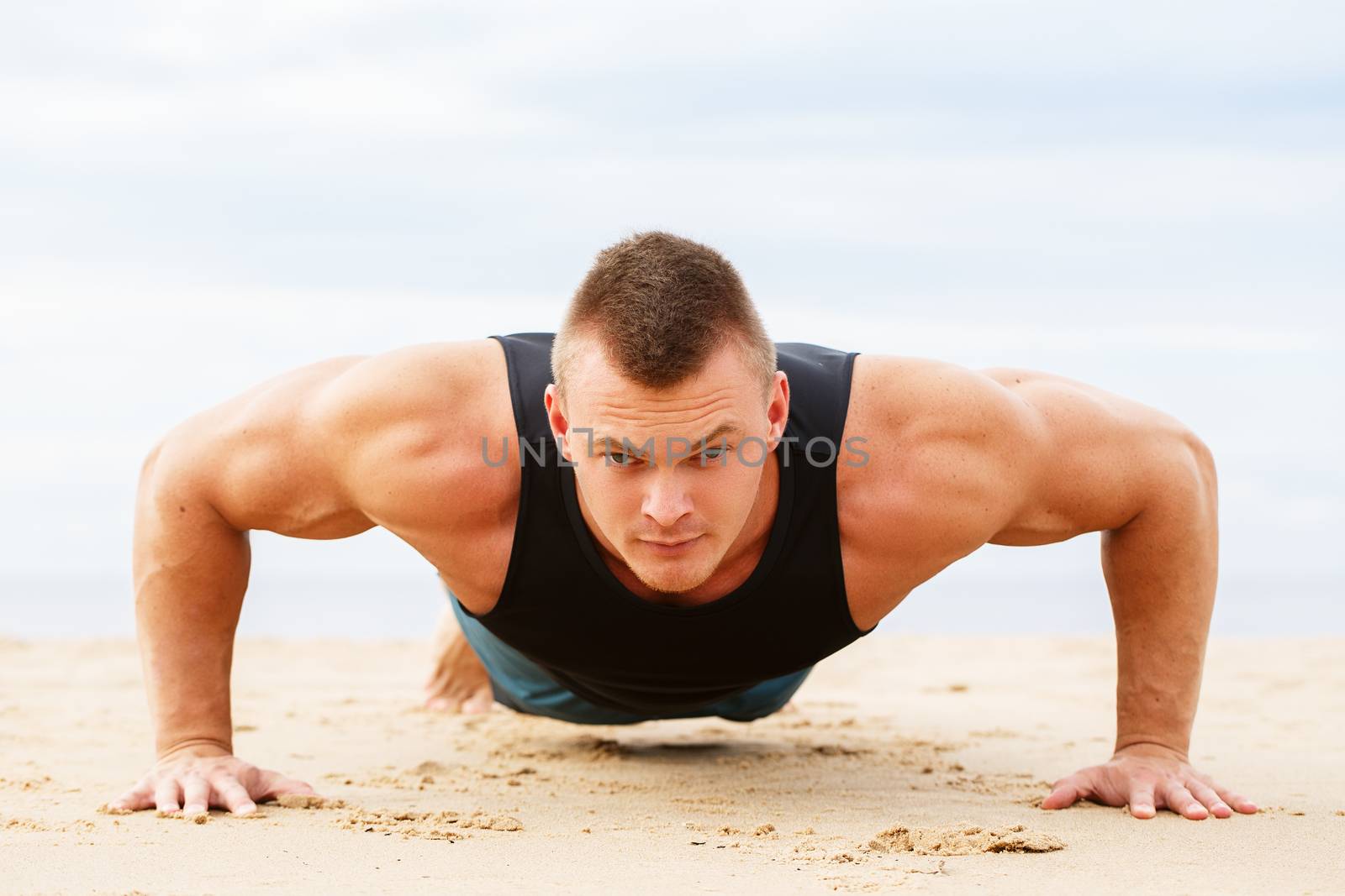 Sport, fitness. Man doing push-up on the beach