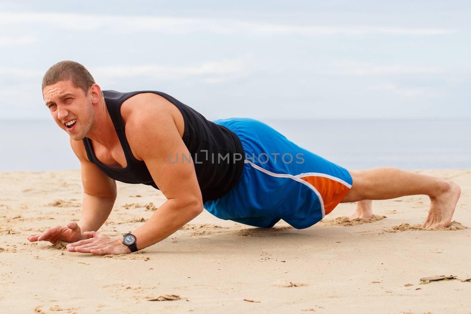 Sport, fitness. Man doing push-up on the beach