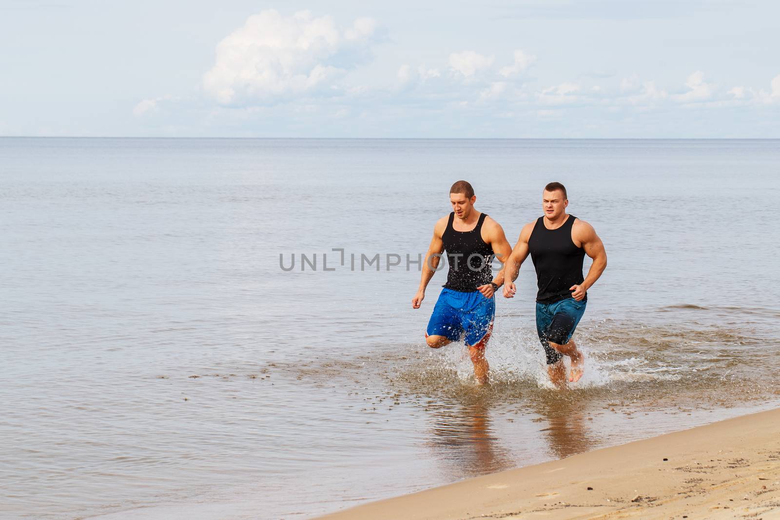 Two guys running on the beach