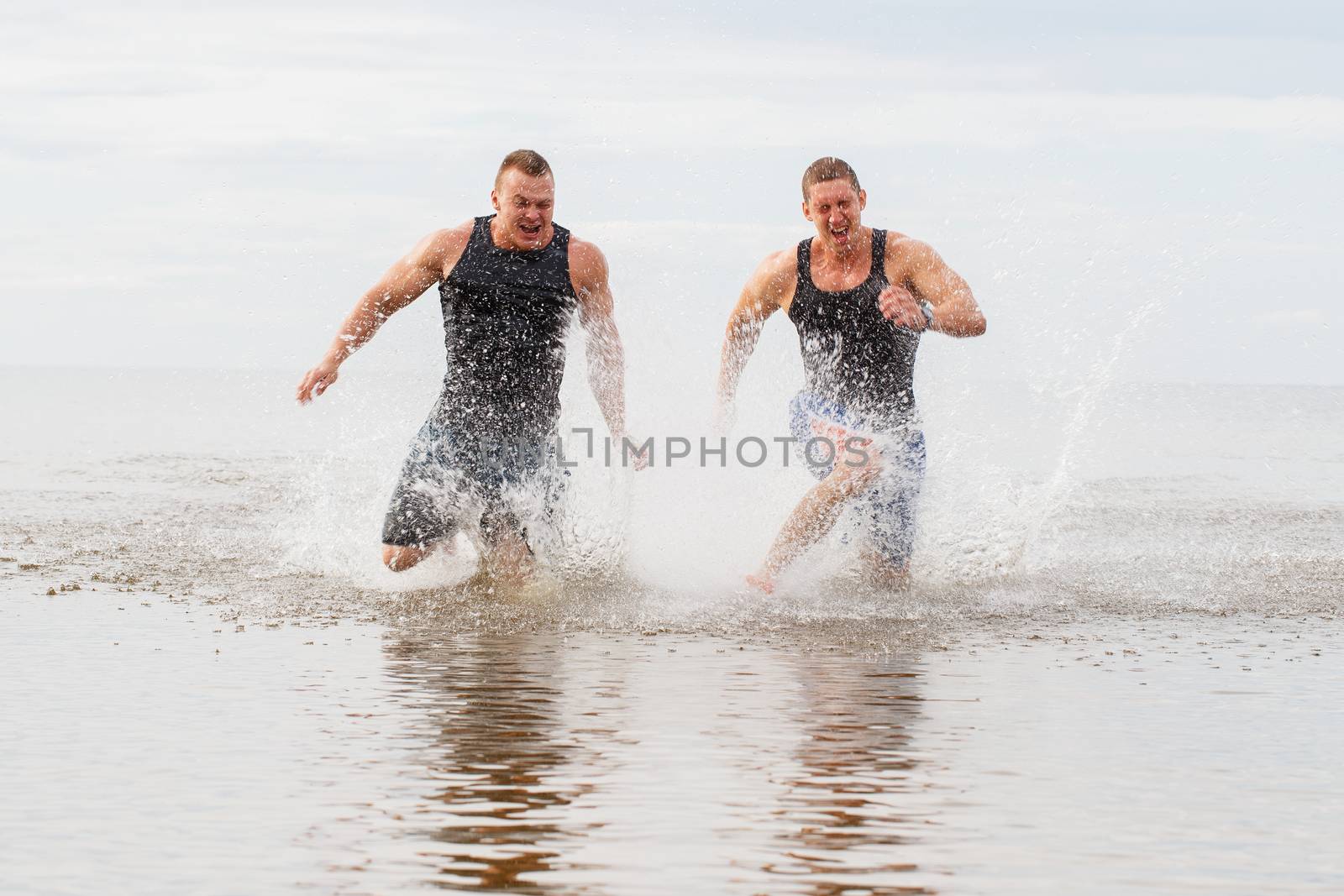 Two guys running on the beach