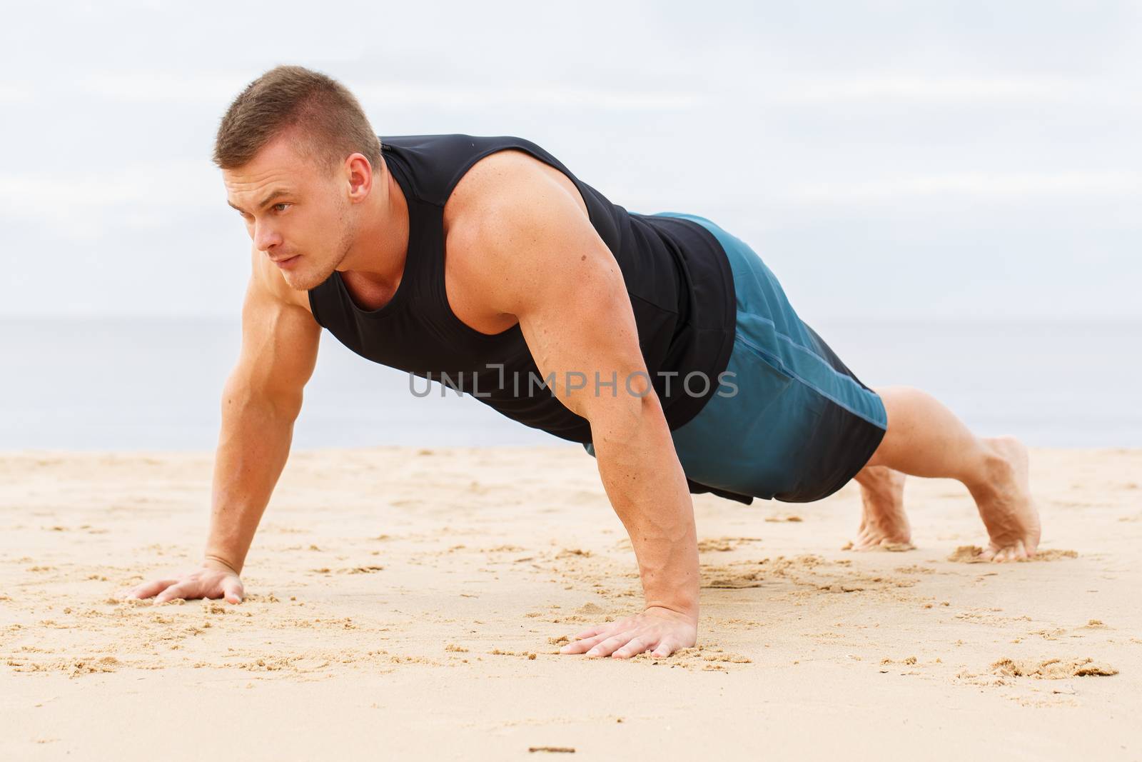 Sport, fitness. Man doing push-up on the beach