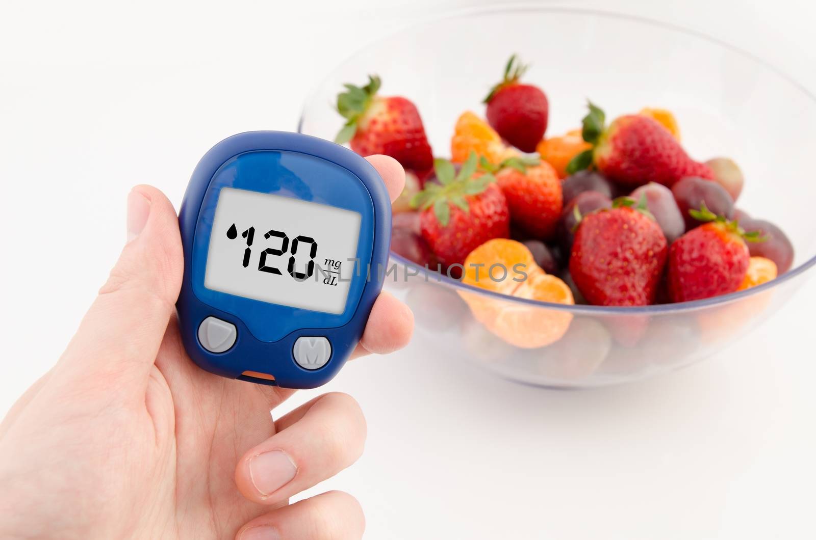 Hand holding meter. Diabetes doing glucose level test. Fruits in background