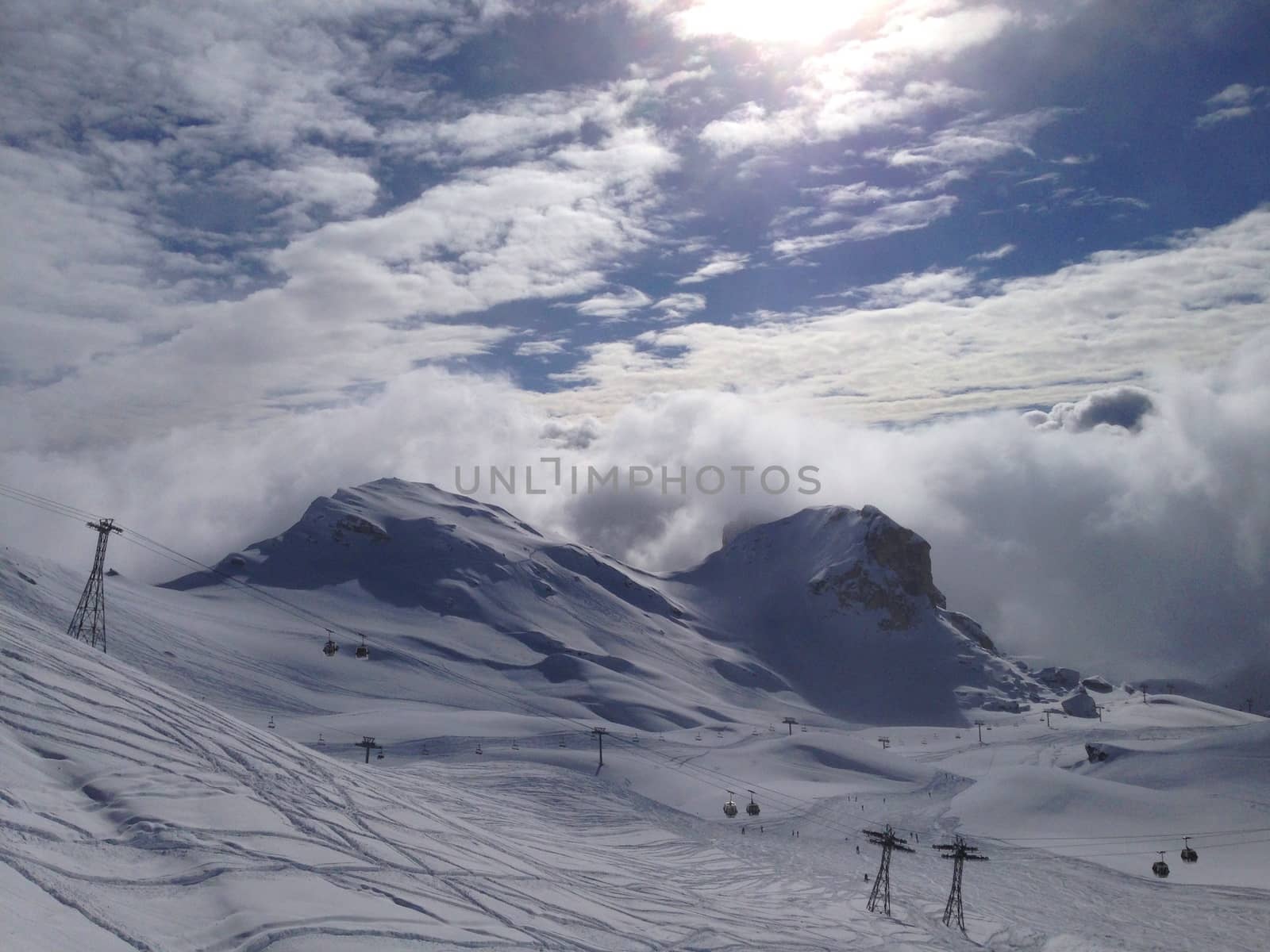 A mountain ski scene under a bright blue sky with clouds by chrisga