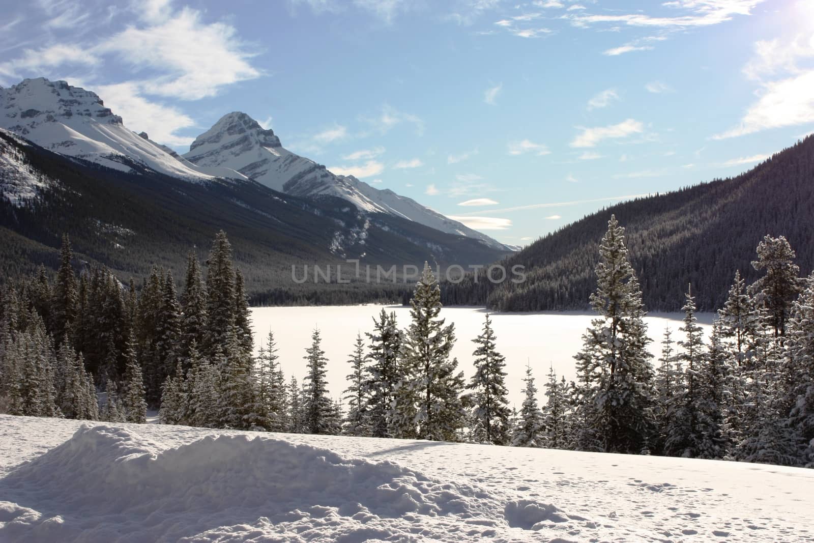 a frozen lake in front of a mountain in the rockies under blue s by chrisga