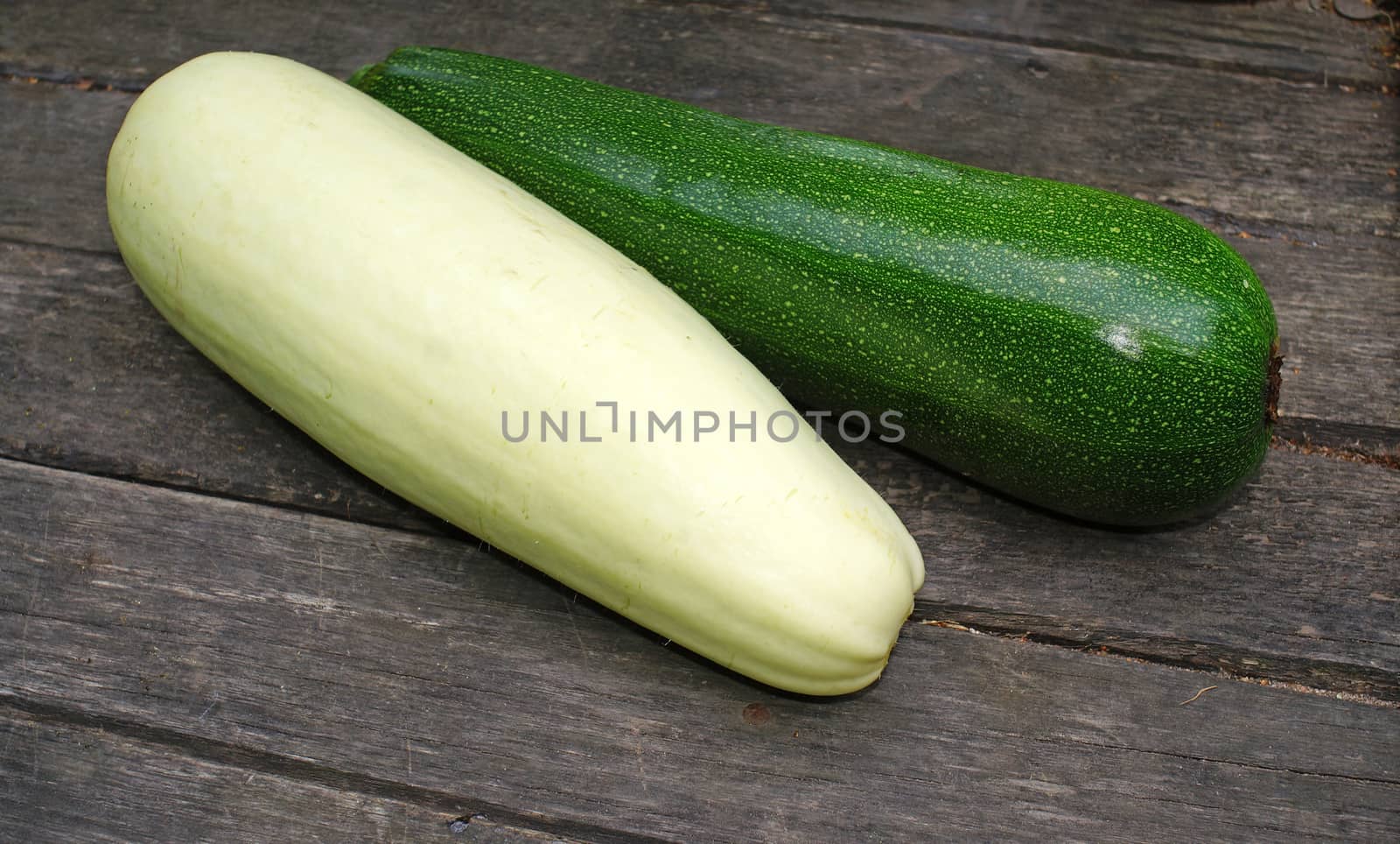 Green and white zucchini on a wooden table                               