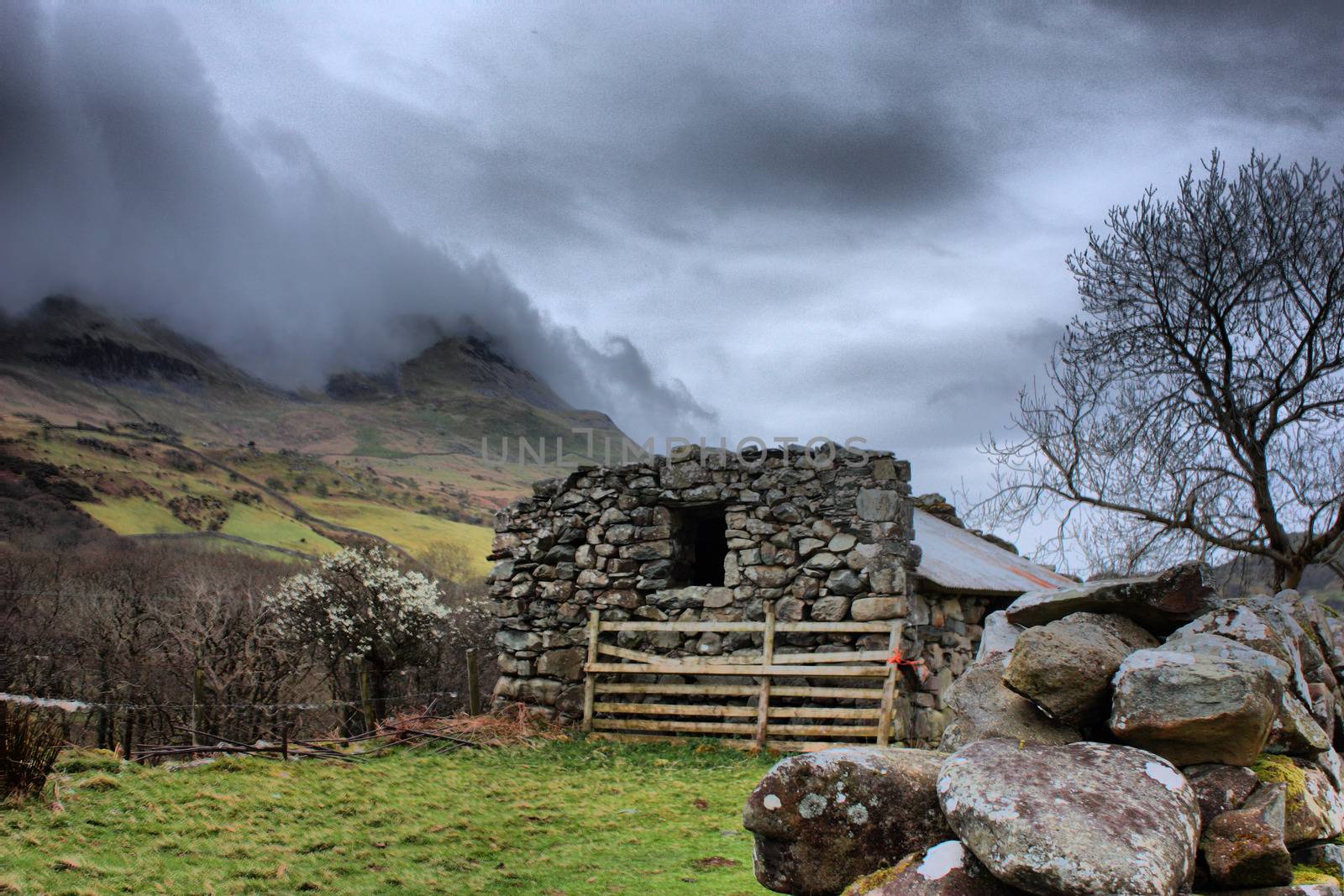 stone building in front of cadair idris mountain range in snowdo by chrisga