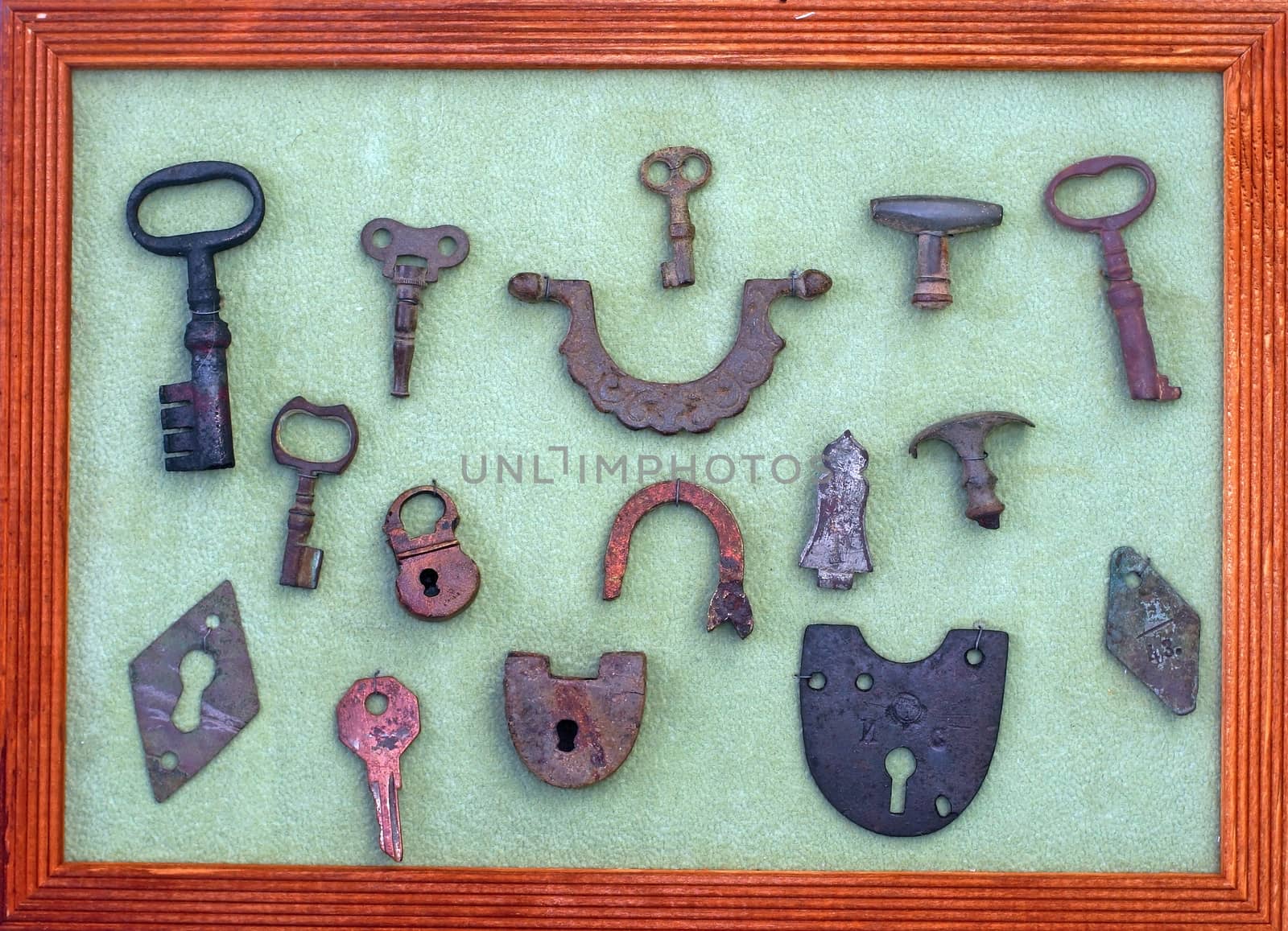 A collection of very old keys and locks in a wooden frame