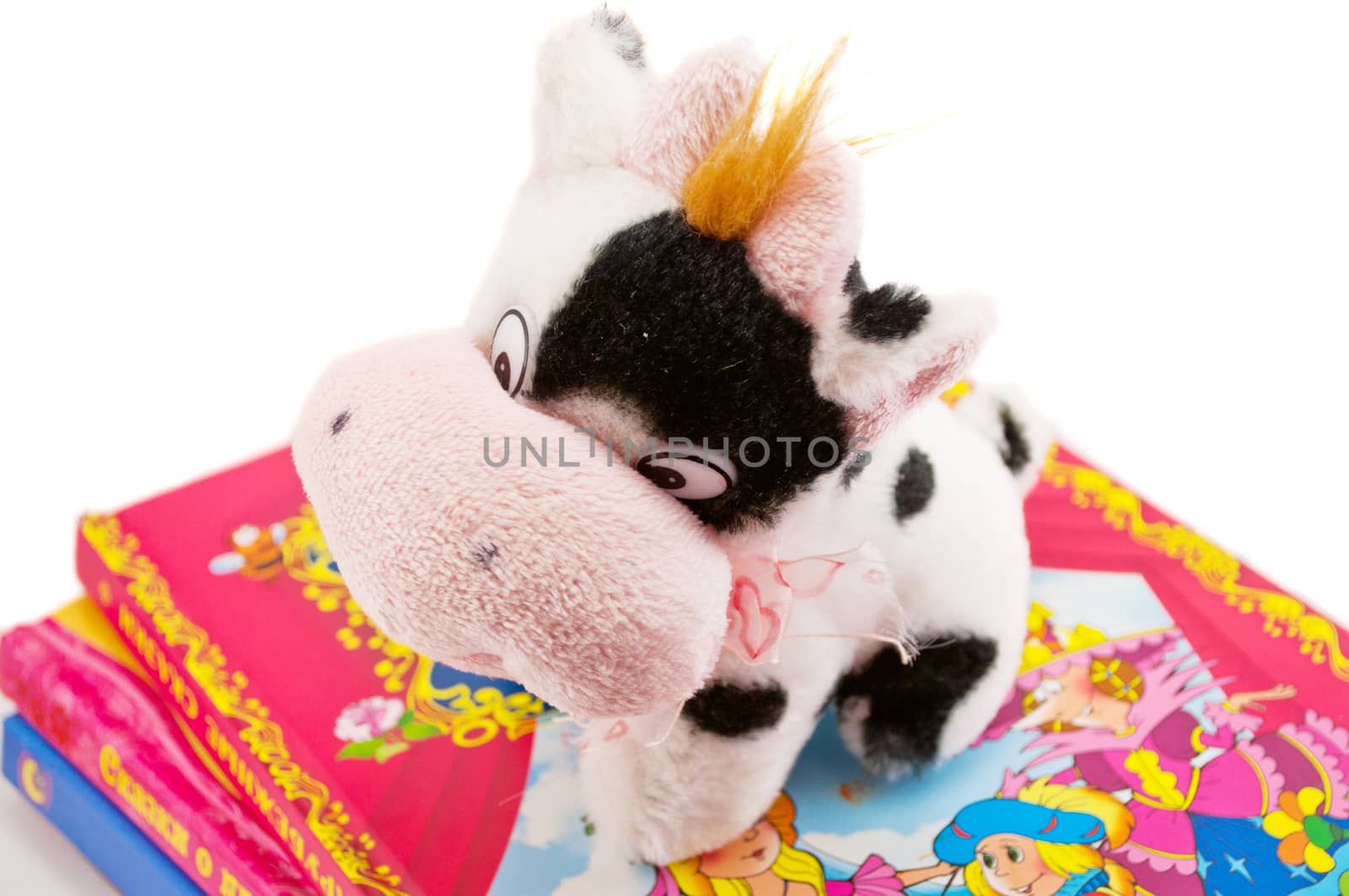 soft toy cow on a pile of books