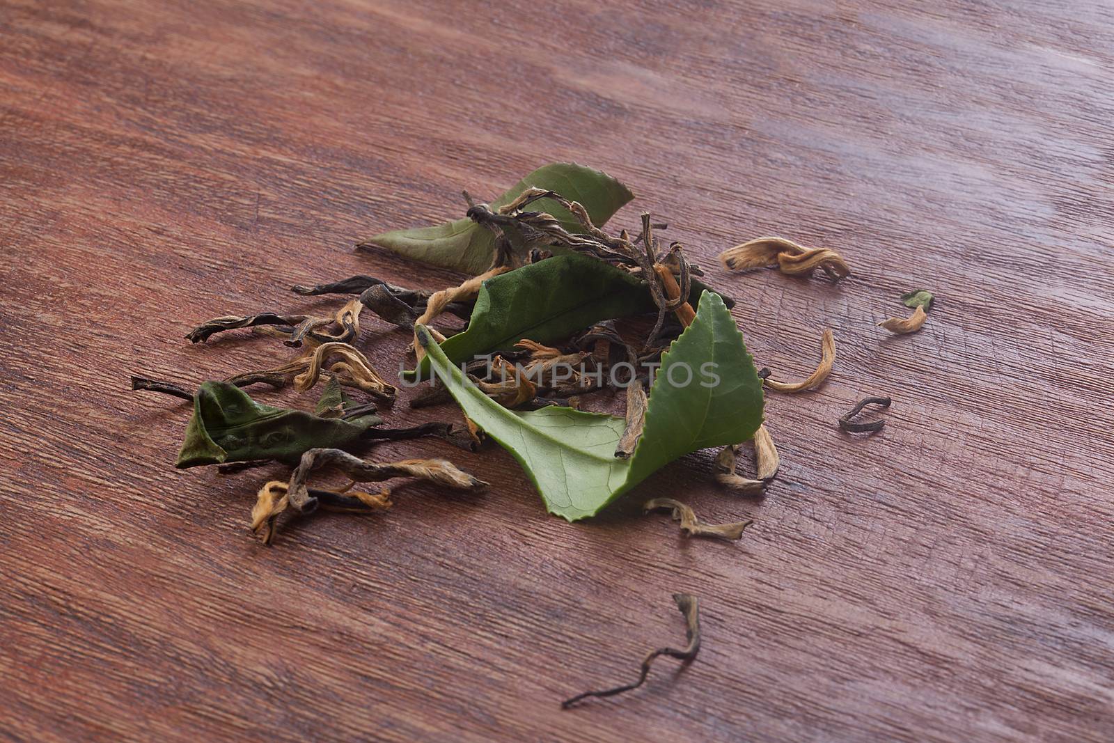 Brown dry and fresh green leaves of tea on the wooden board