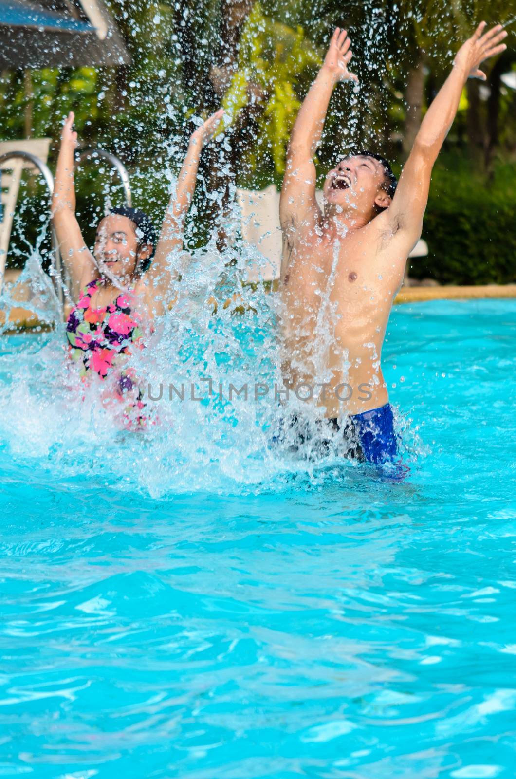 Father and daughter are having fun splashing in the pool