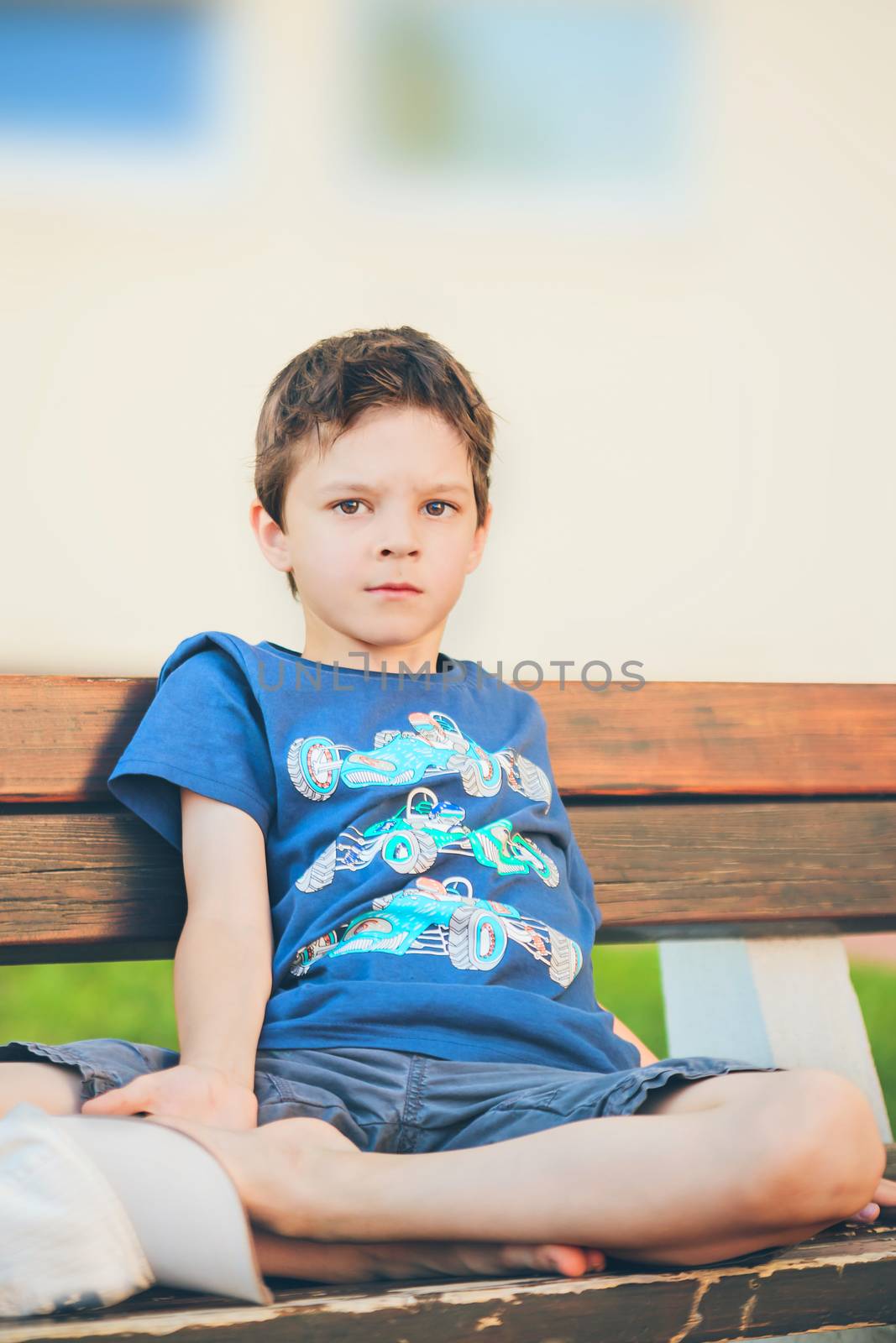 sad boy sitting on a bench and looking into the camera