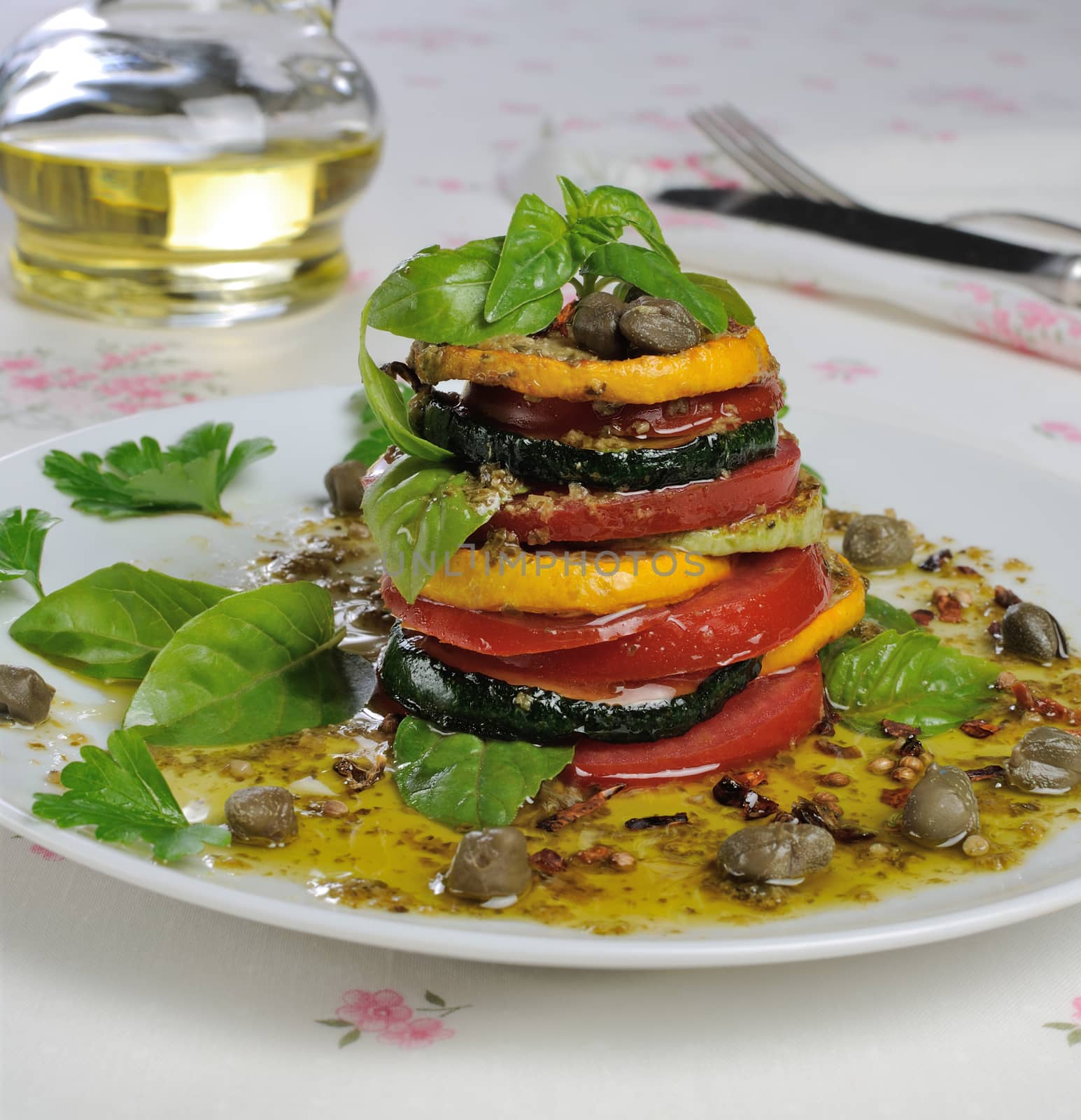 Appetizer of zucchini with tomato, pesto and capers