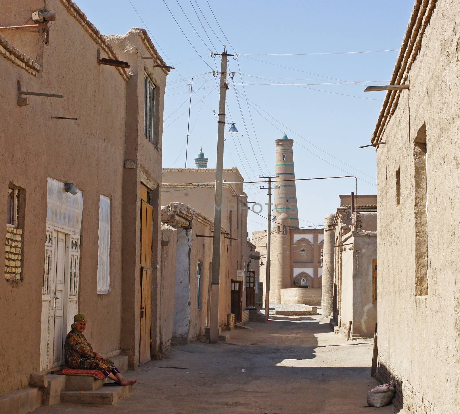 KHIVA, UZBEKISTAN - MAY 20, 2012: Old woman sitting in the shadow on a hot day in Khiva on May 20, 2012 in Uzbekistan, Asia.