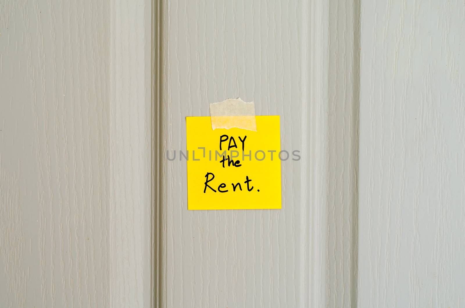 sticky note write a message pay the rent on wood door background