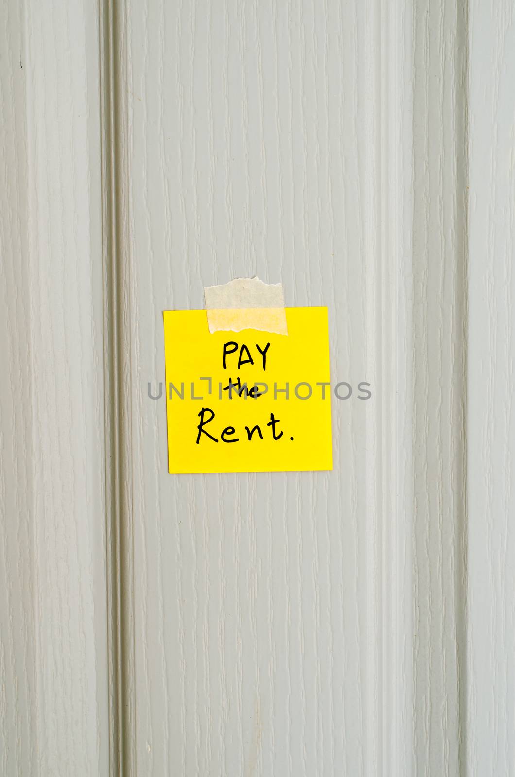 sticky note write a message pay the rent on wood door background