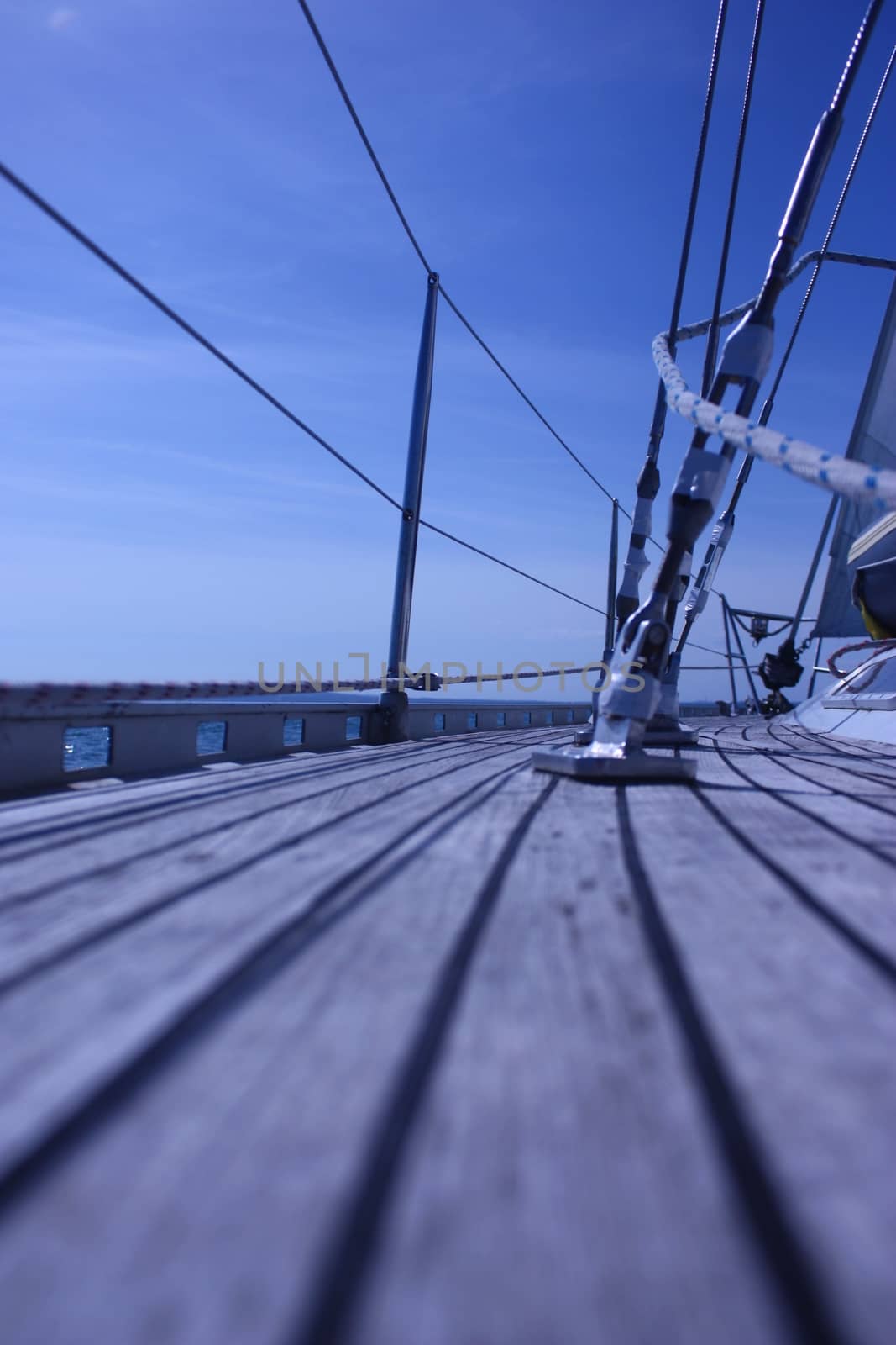 The curved teak deck of a yacht sailing at sea by chrisga