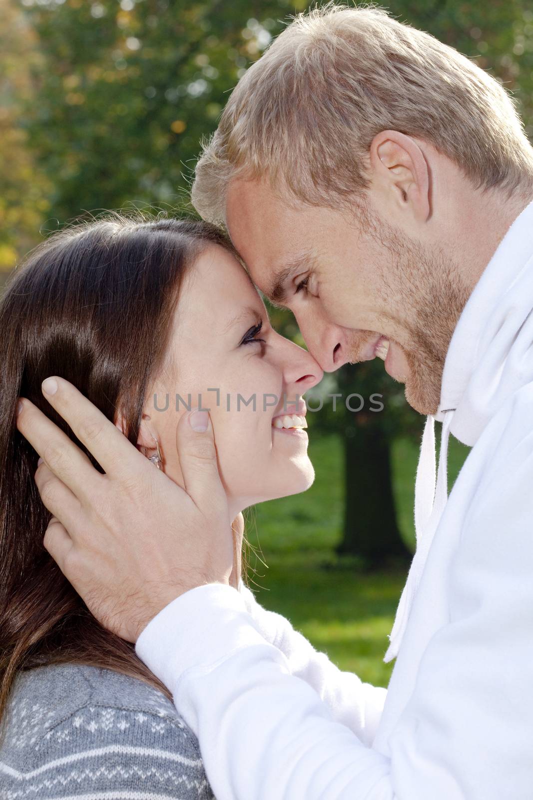 portrait of a happy young couple in the park, embracing, smiling.