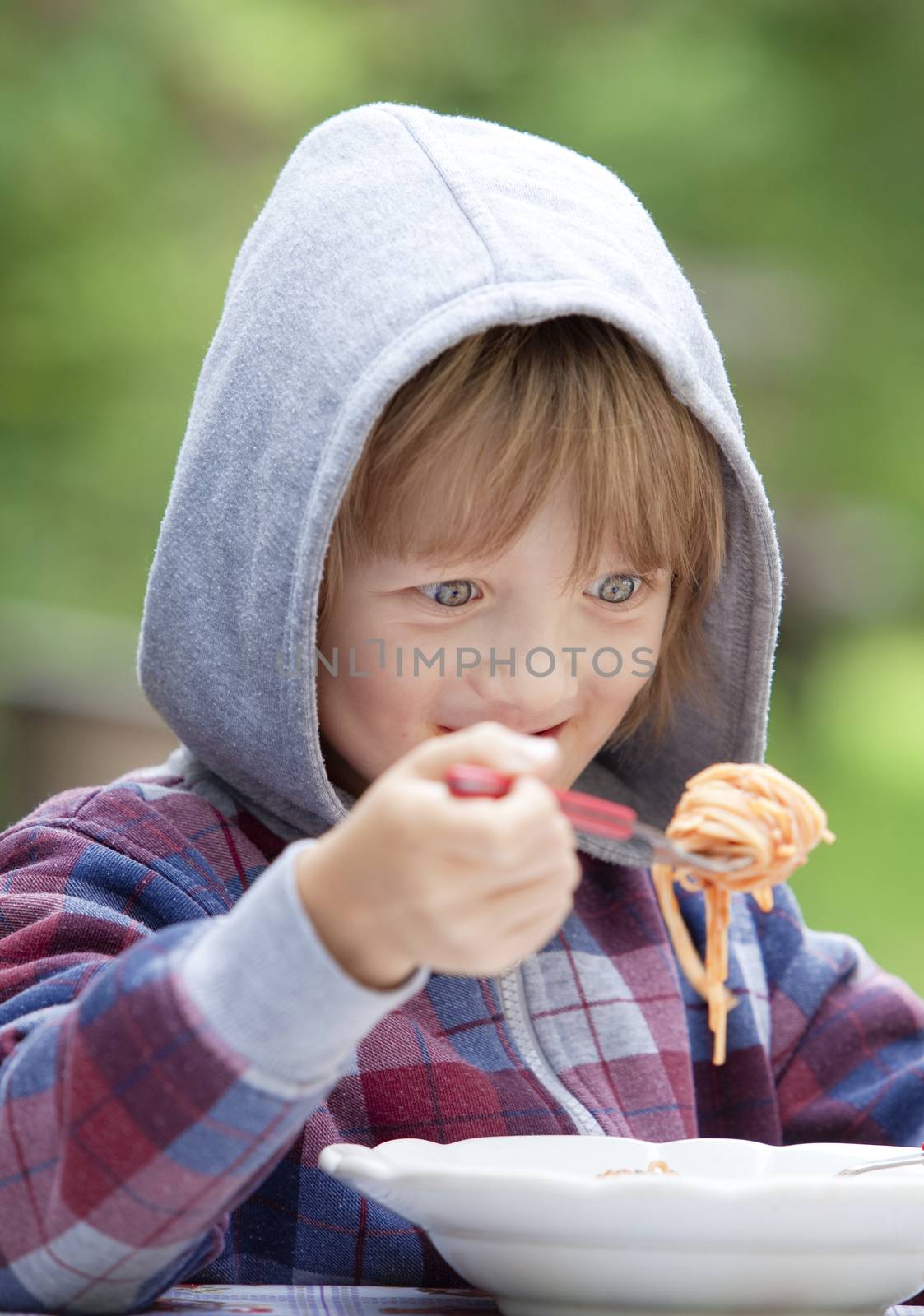 Boy with Blond Hair in Hood Eating Pasta