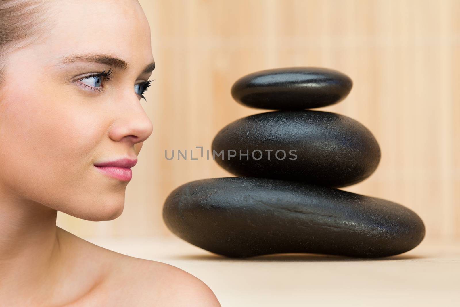 Smiling blonde natural beauty against stack of smooth balancing rocks