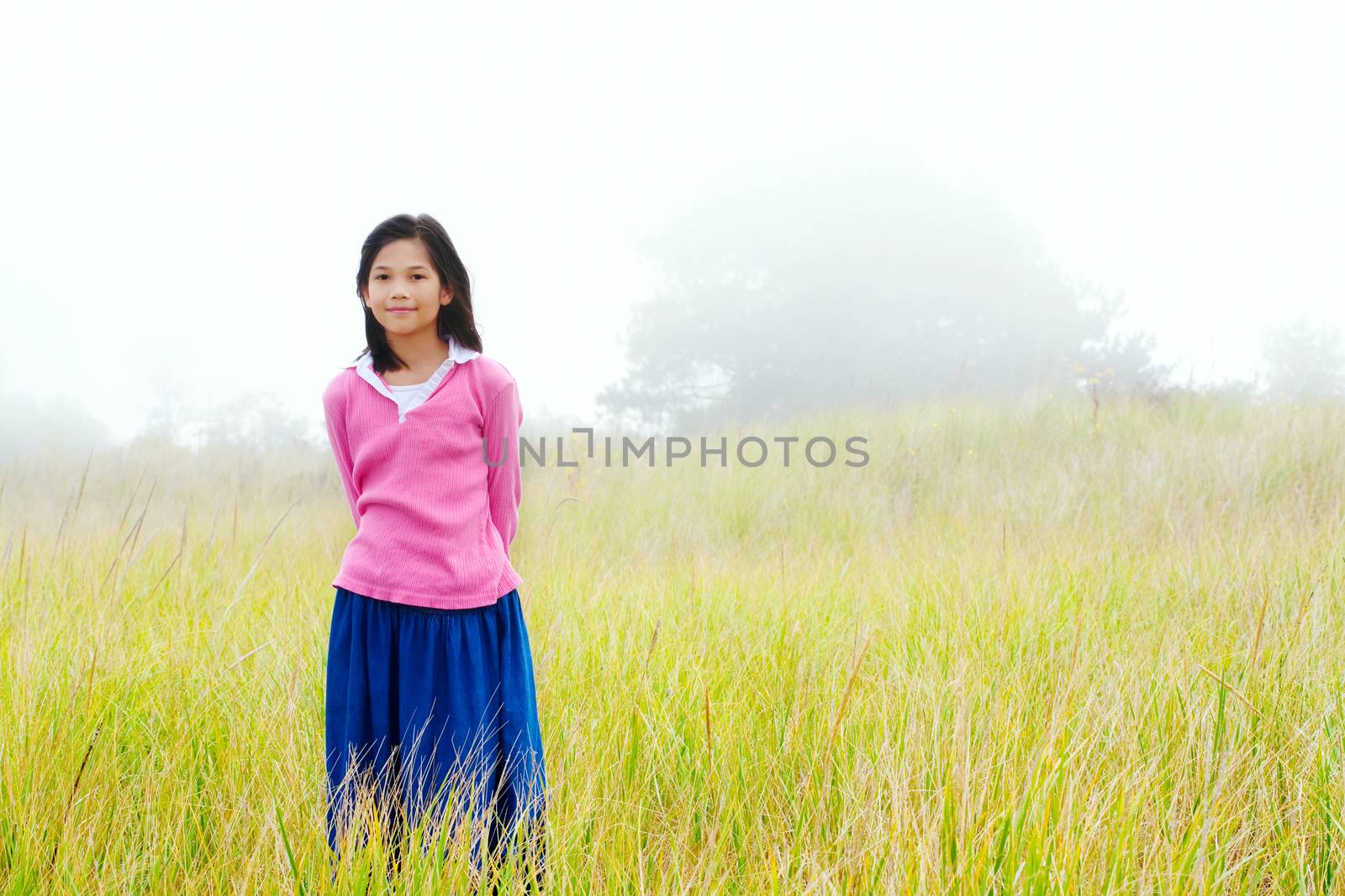 Young girl quietly standing on misty foggy field by jarenwicklund