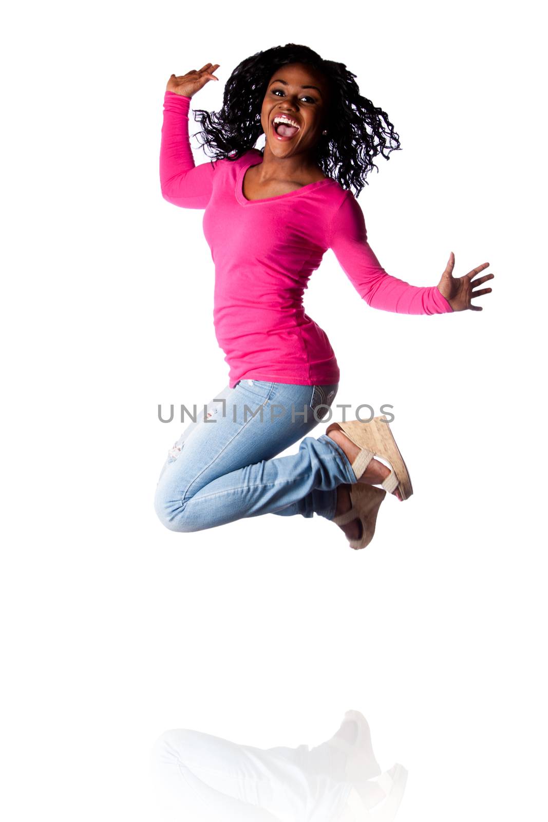 Beautiful young woman jumping of happiness celebrating and cheering, wearing blue jeans and pink shirt.