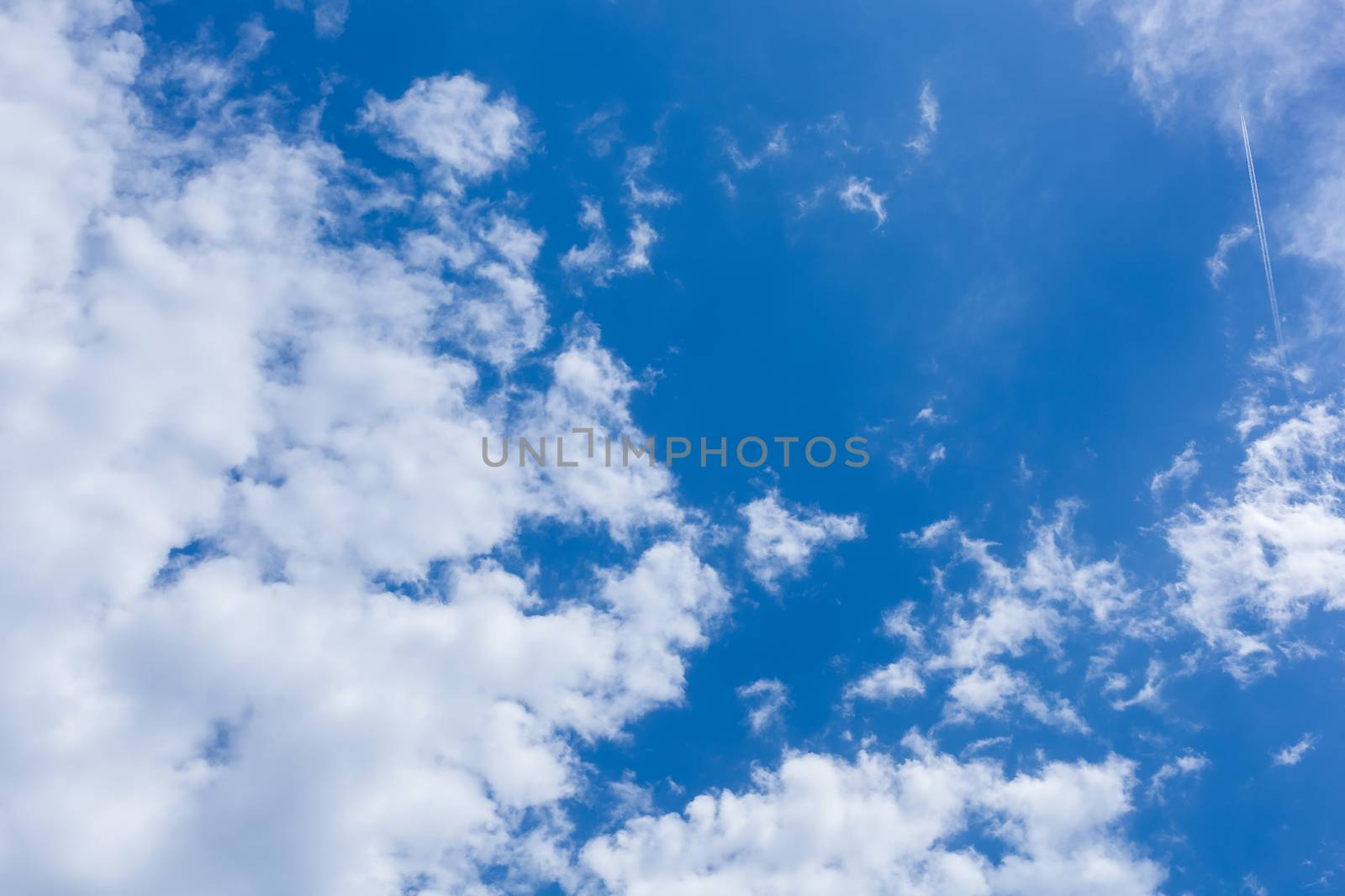 Clouds and jet plane passing on blue sunny sky
