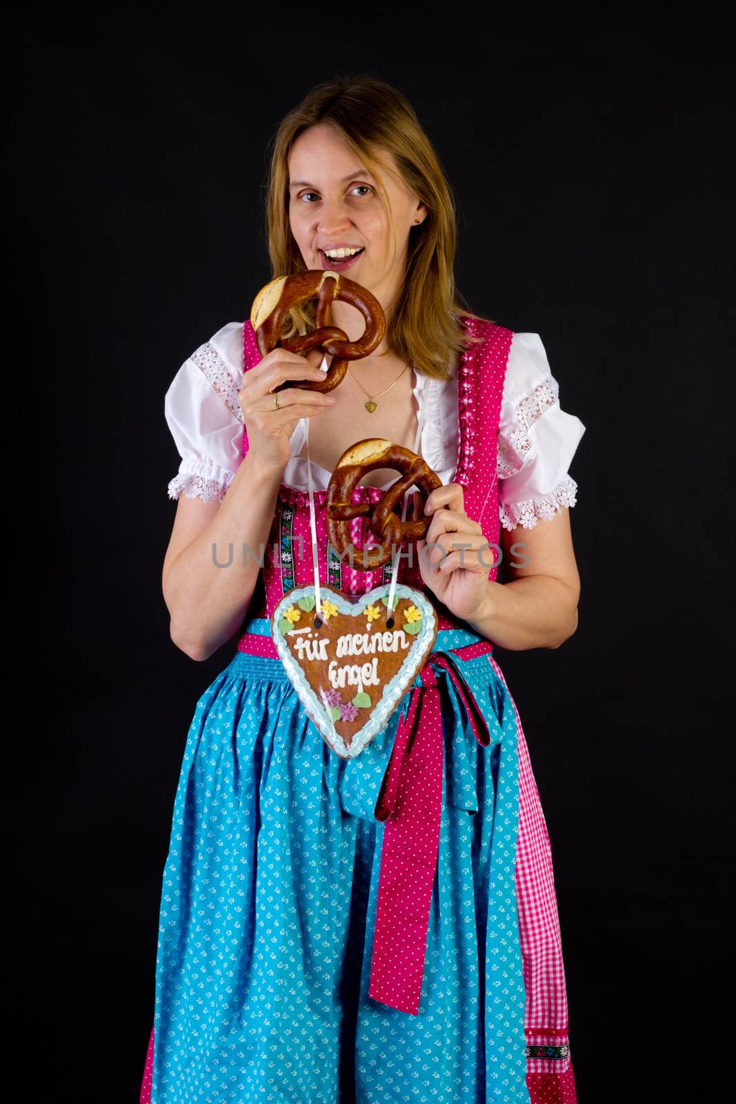 Woman in dirndl eating pretzel by gwolters