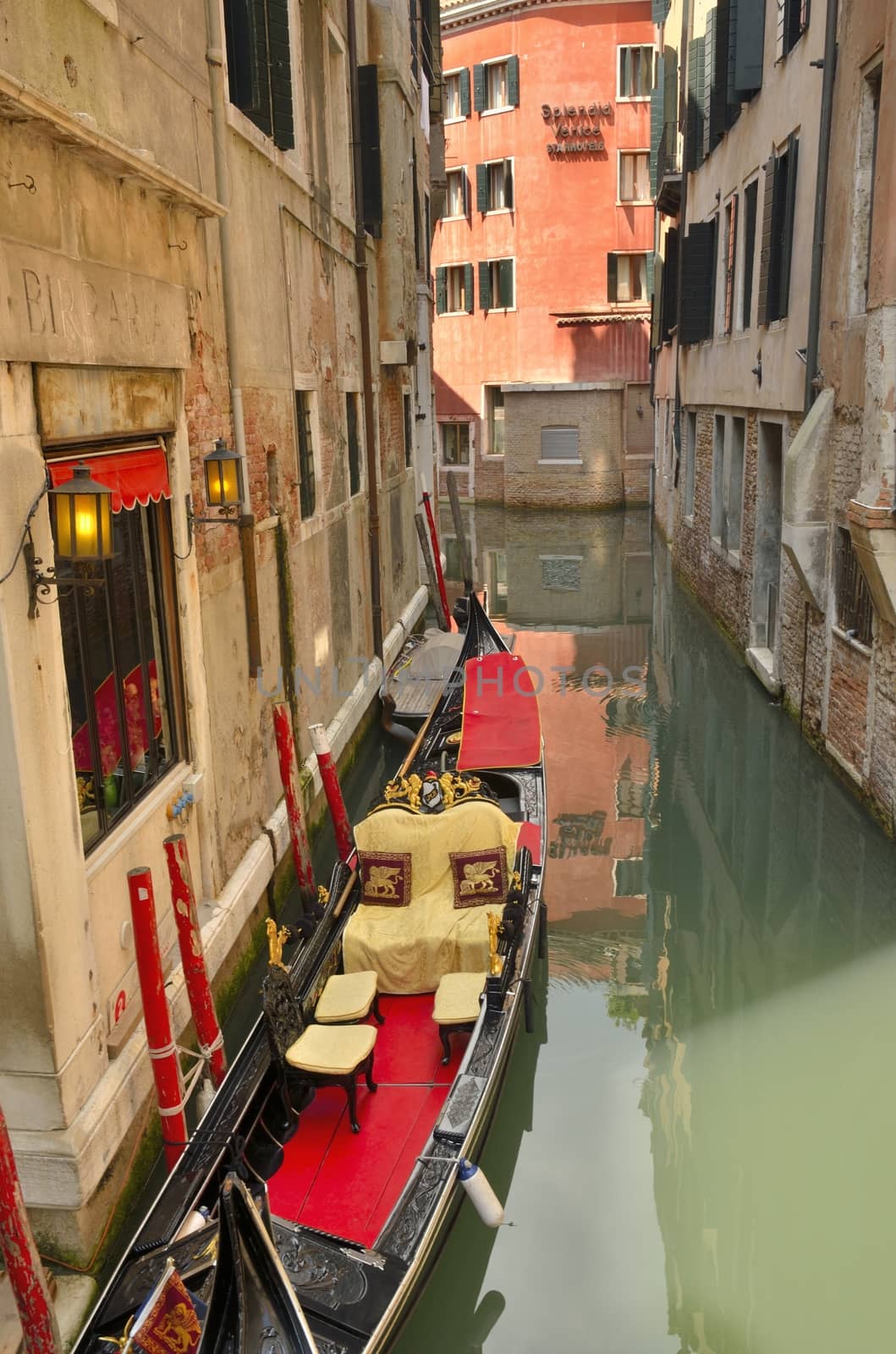 Elegant Venetian gondola on the side of a narrow canal in Venice, Italy