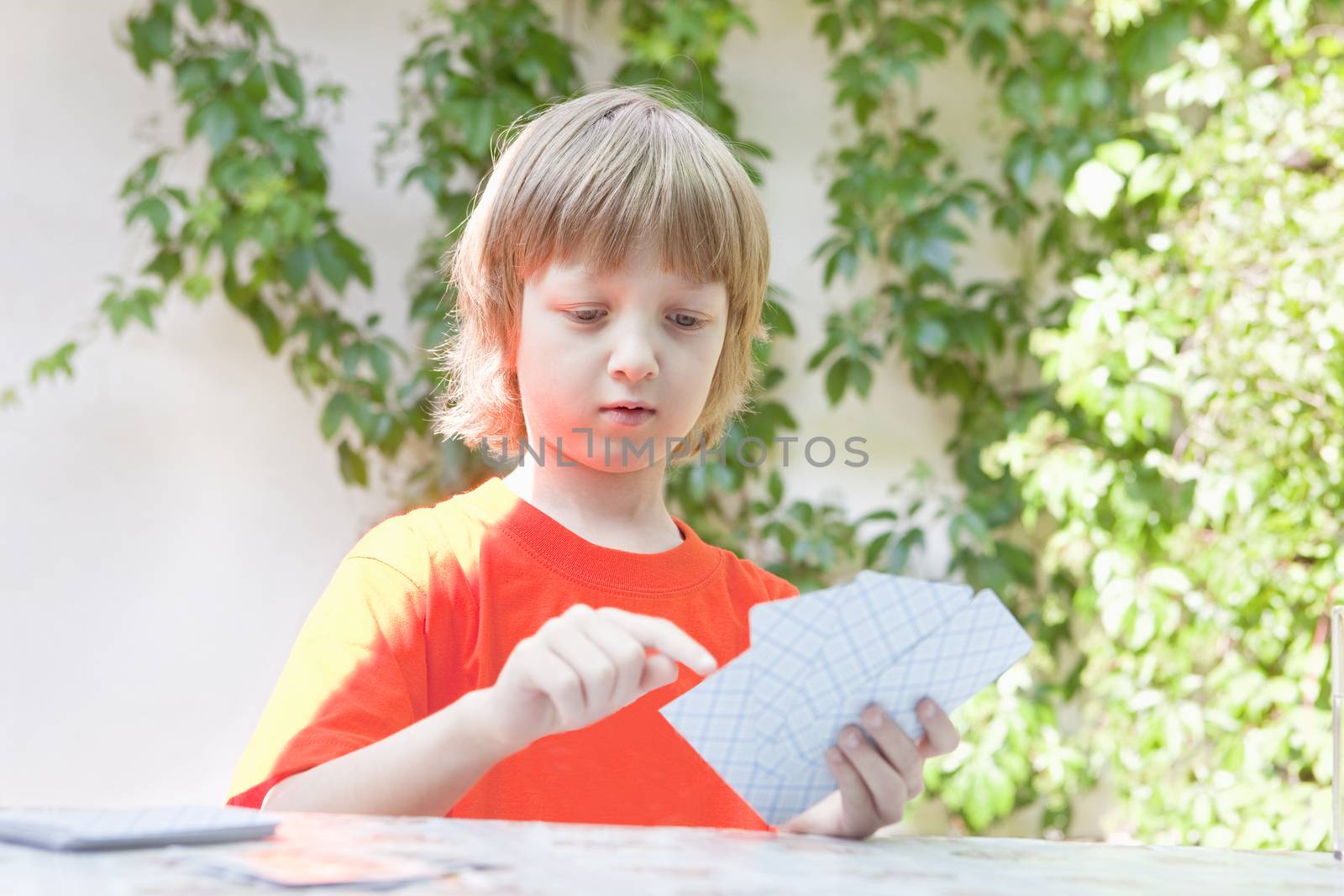 Boy with Blond Hair Playing Cards by courtyardpix