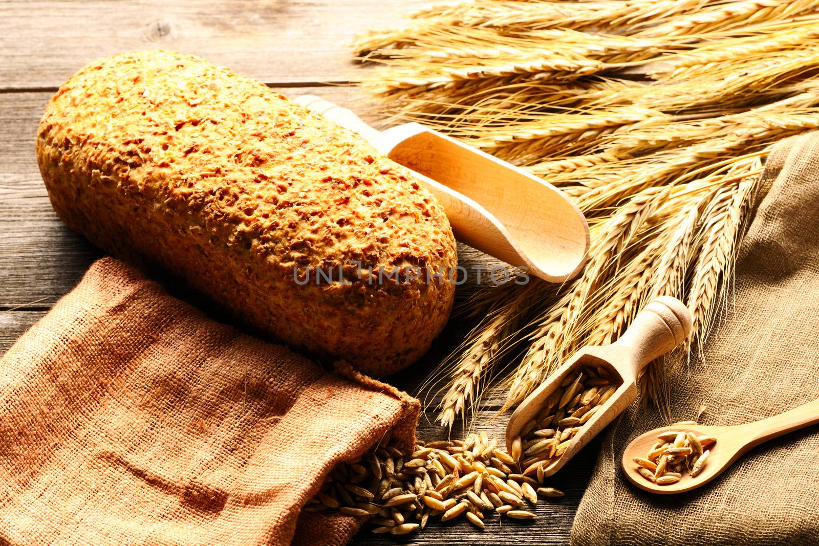 Rye spikelets and bread still life on wooden background by haveseen