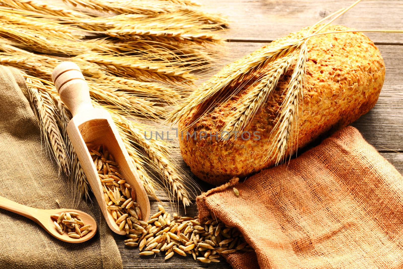 Rye spikelets and bread still life on wooden background by haveseen