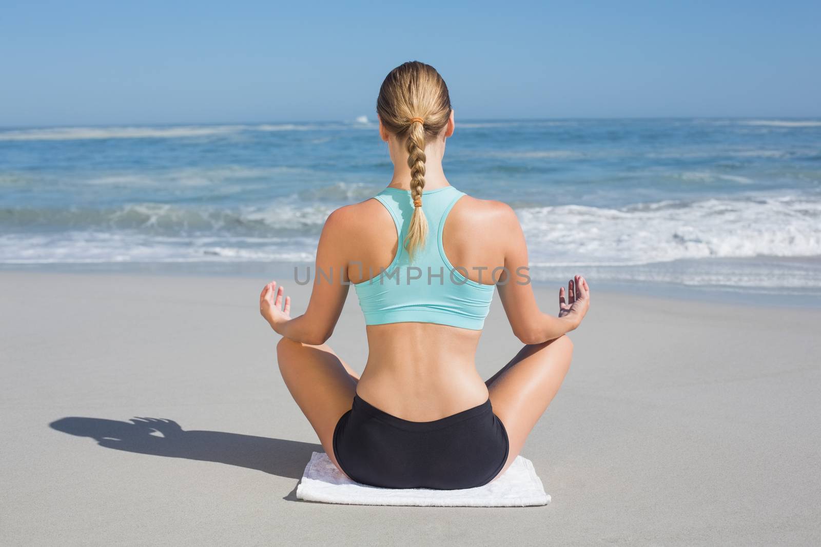 Fit woman sitting on the beach in lotus pose by Wavebreakmedia