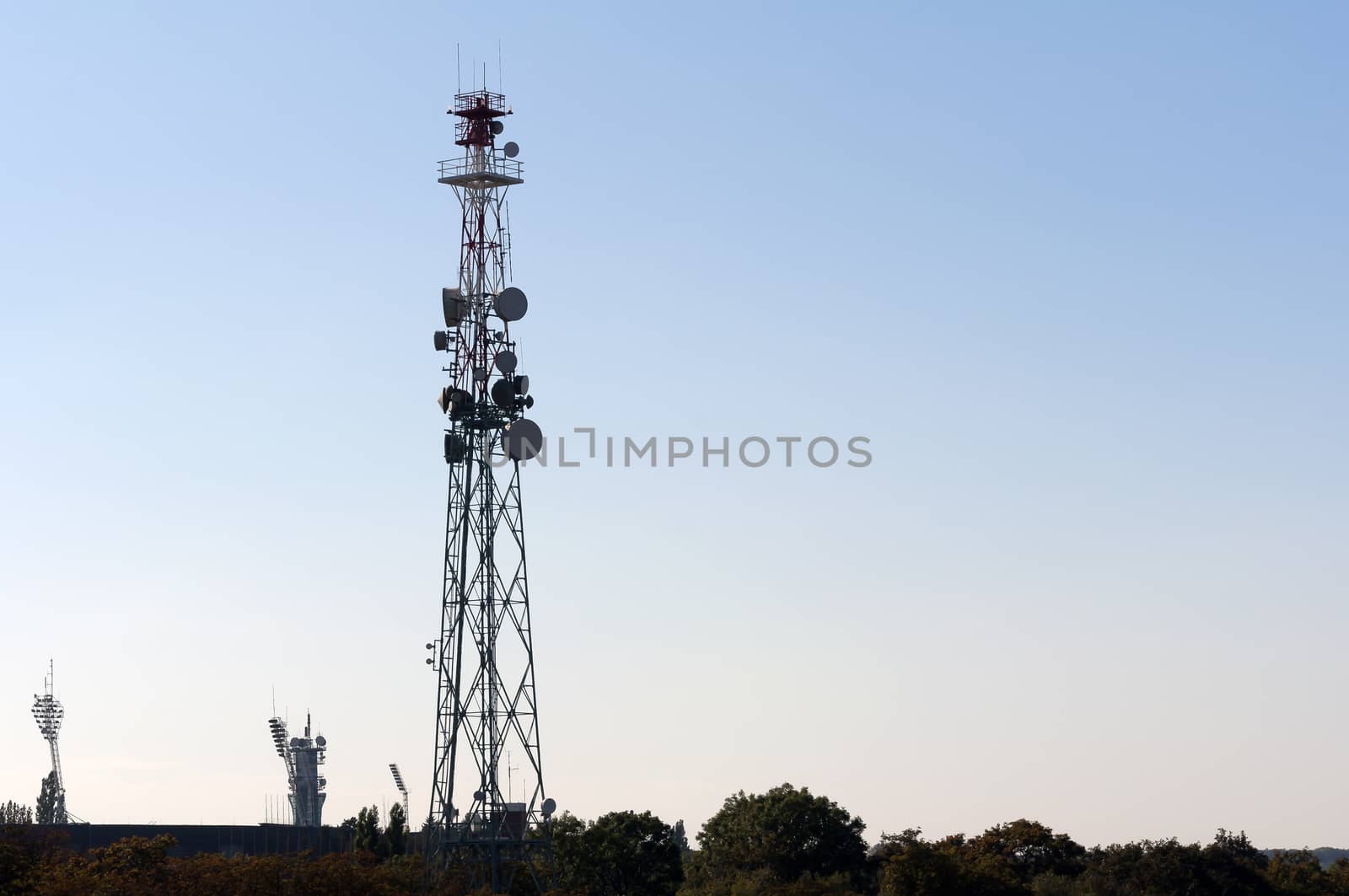 Telecommunications tower with antennas under blue sunset skies.