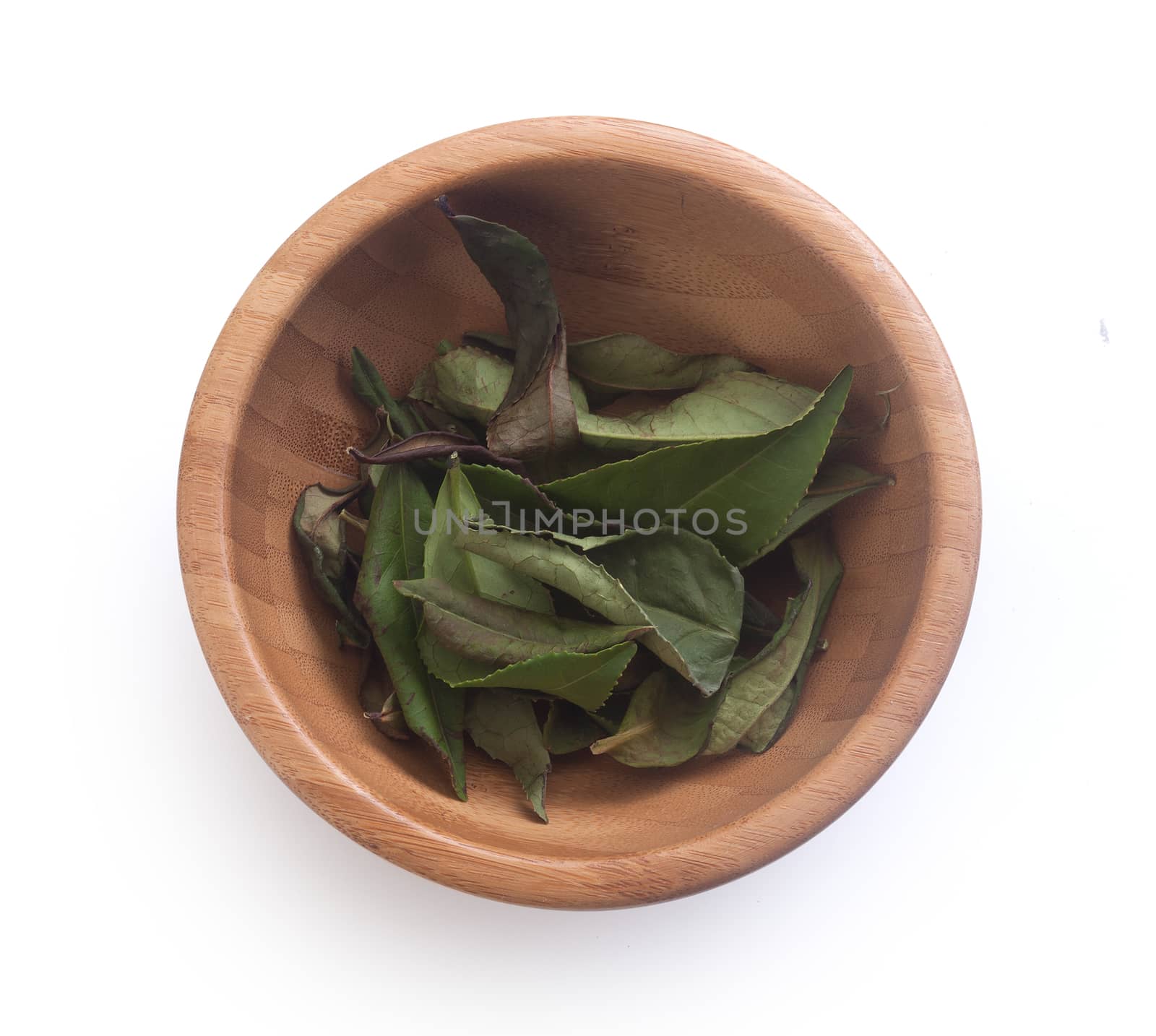 Wooden bowl with dried green tea leaves on the white background