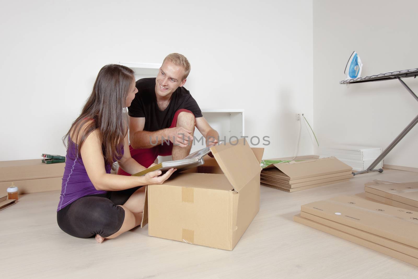 Young Couple Moving, Looking at Old Pictures by courtyardpix