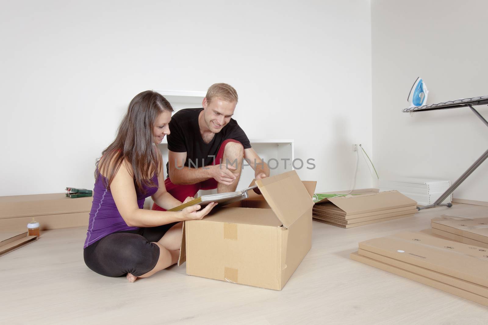 Young Couple Moving, Looking at Old Pictures by courtyardpix