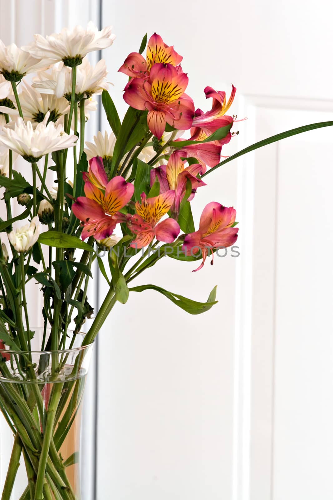 Close up of a flower arrangement with lillies in a clear vase.