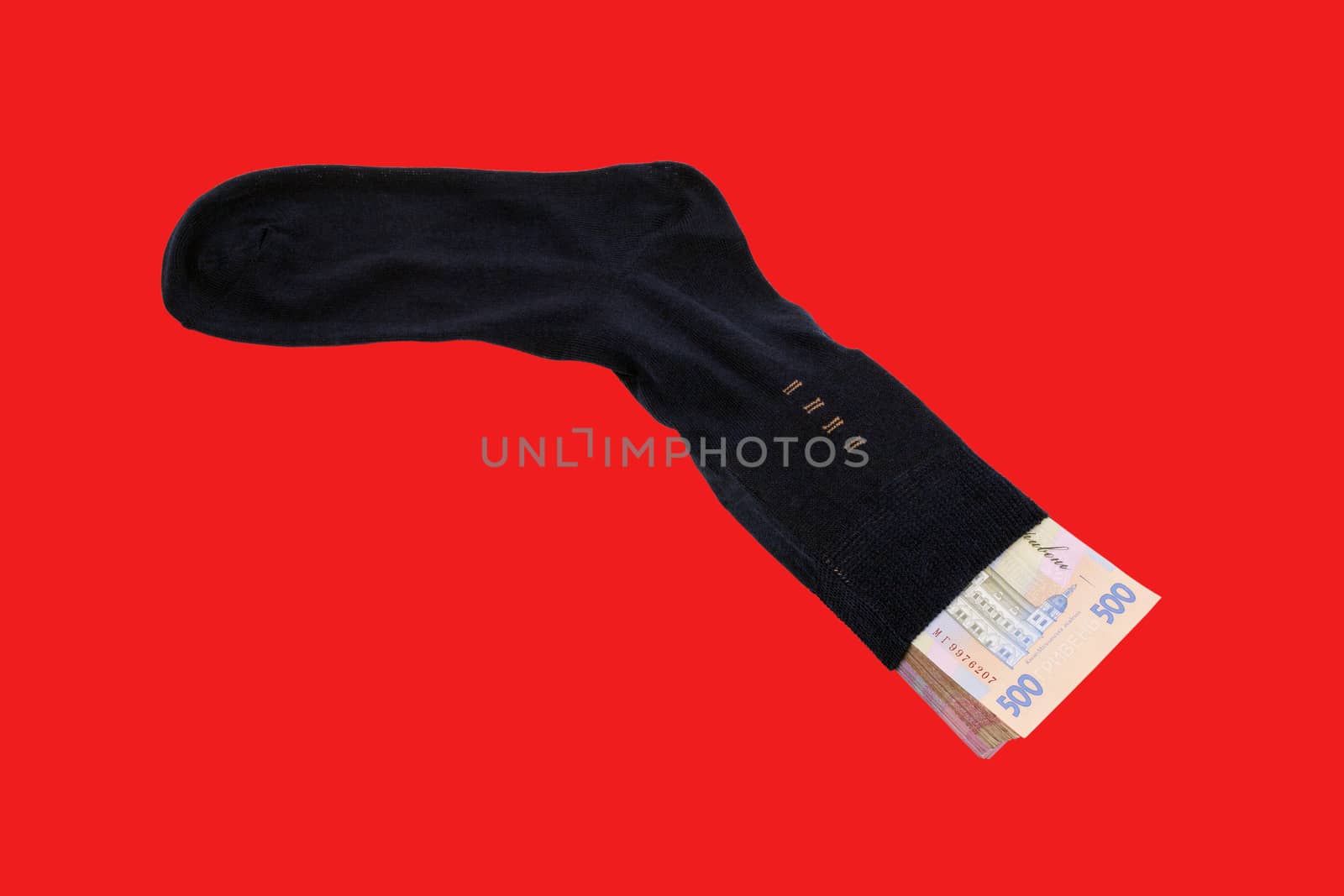 Stack Ukrainian Banknotes five hryvnia in black men's socks on a red background