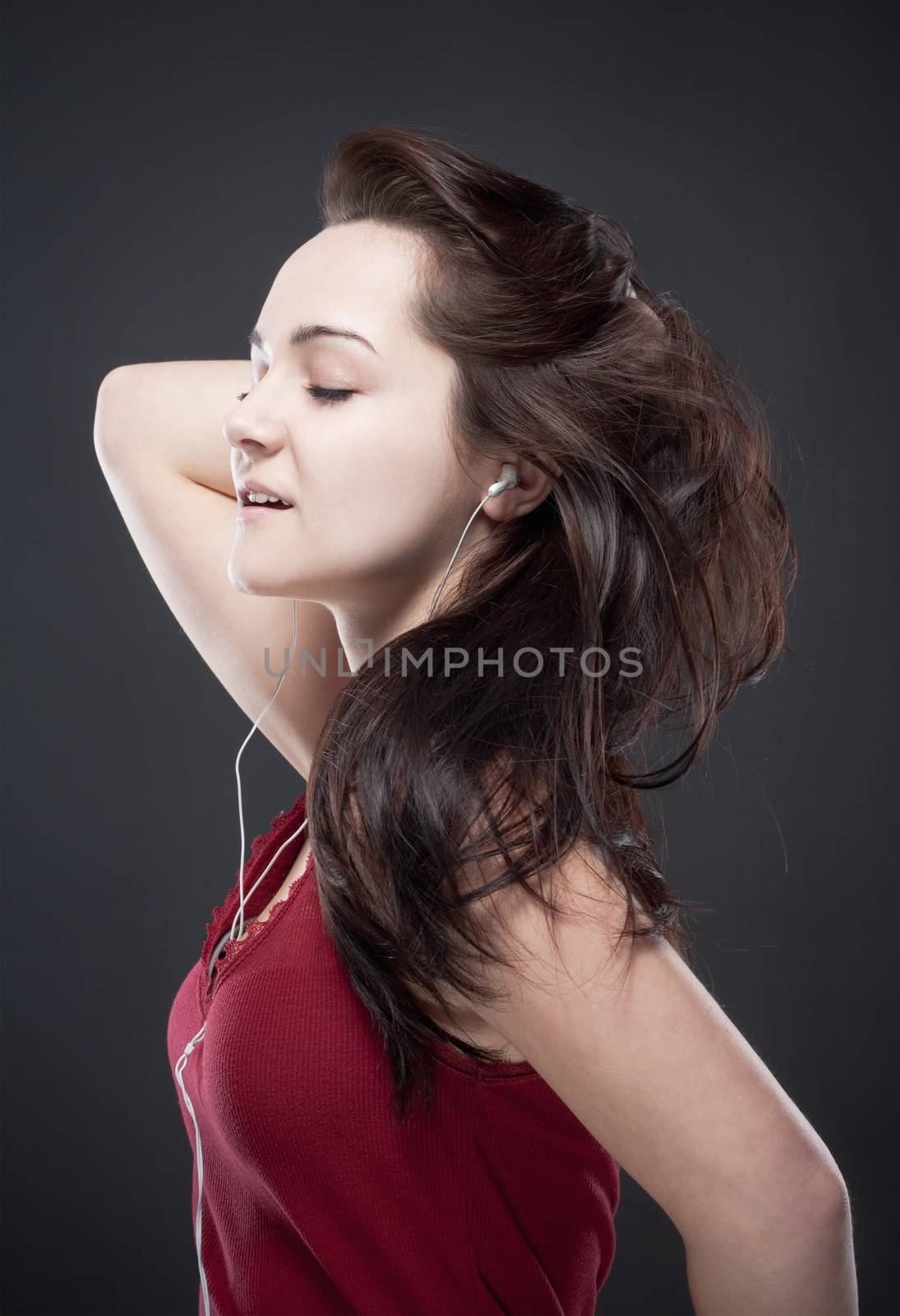 teenage girl listening to music on her personal stereo - isolated on gray