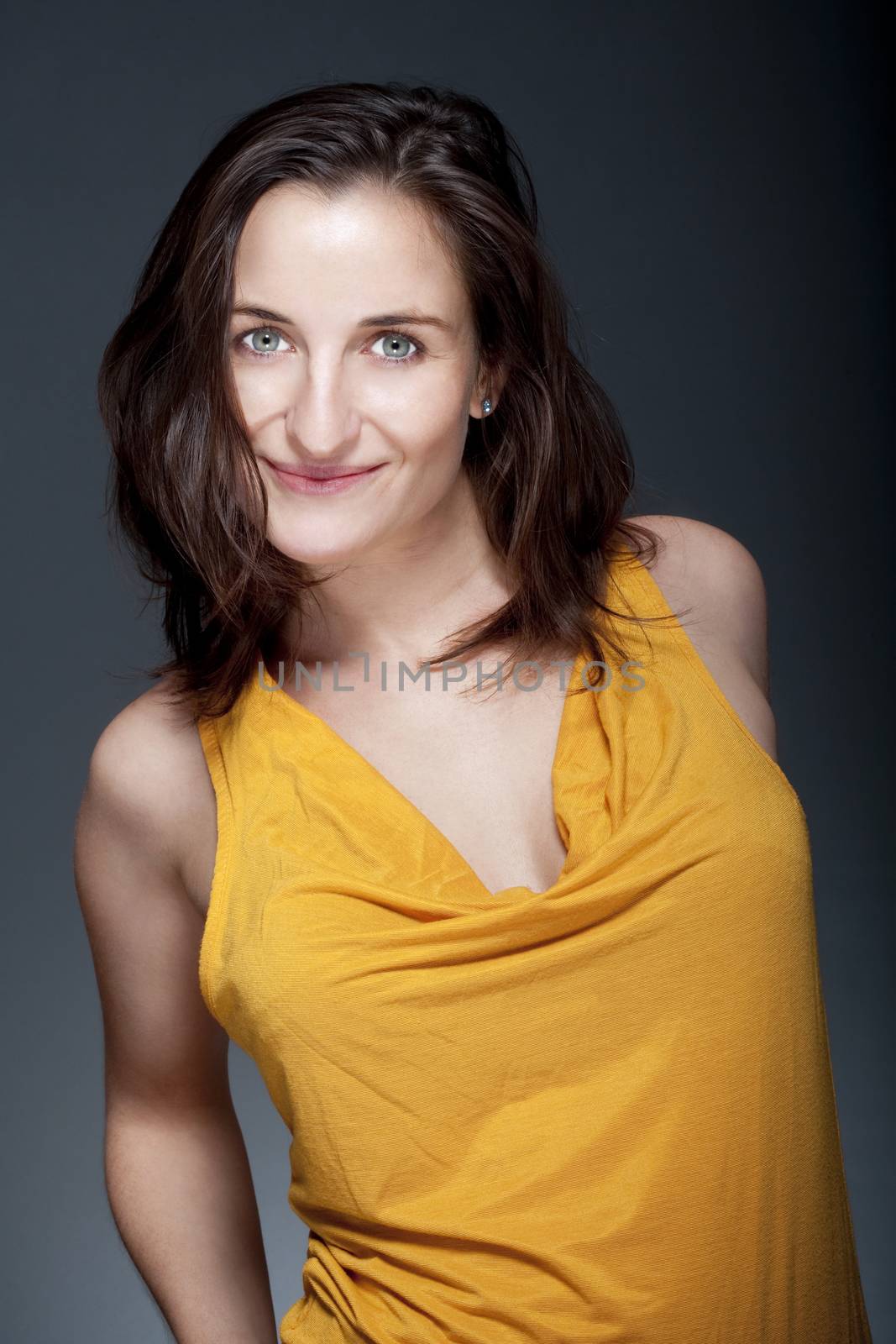 portrait of beautiful woman with brown hair smiling - gray background