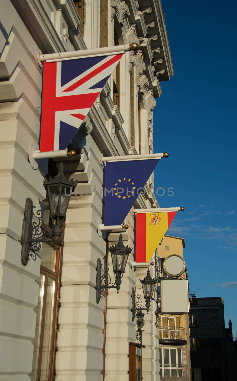 the flags of the UK, Spain and the European Union, hanging outside a European building