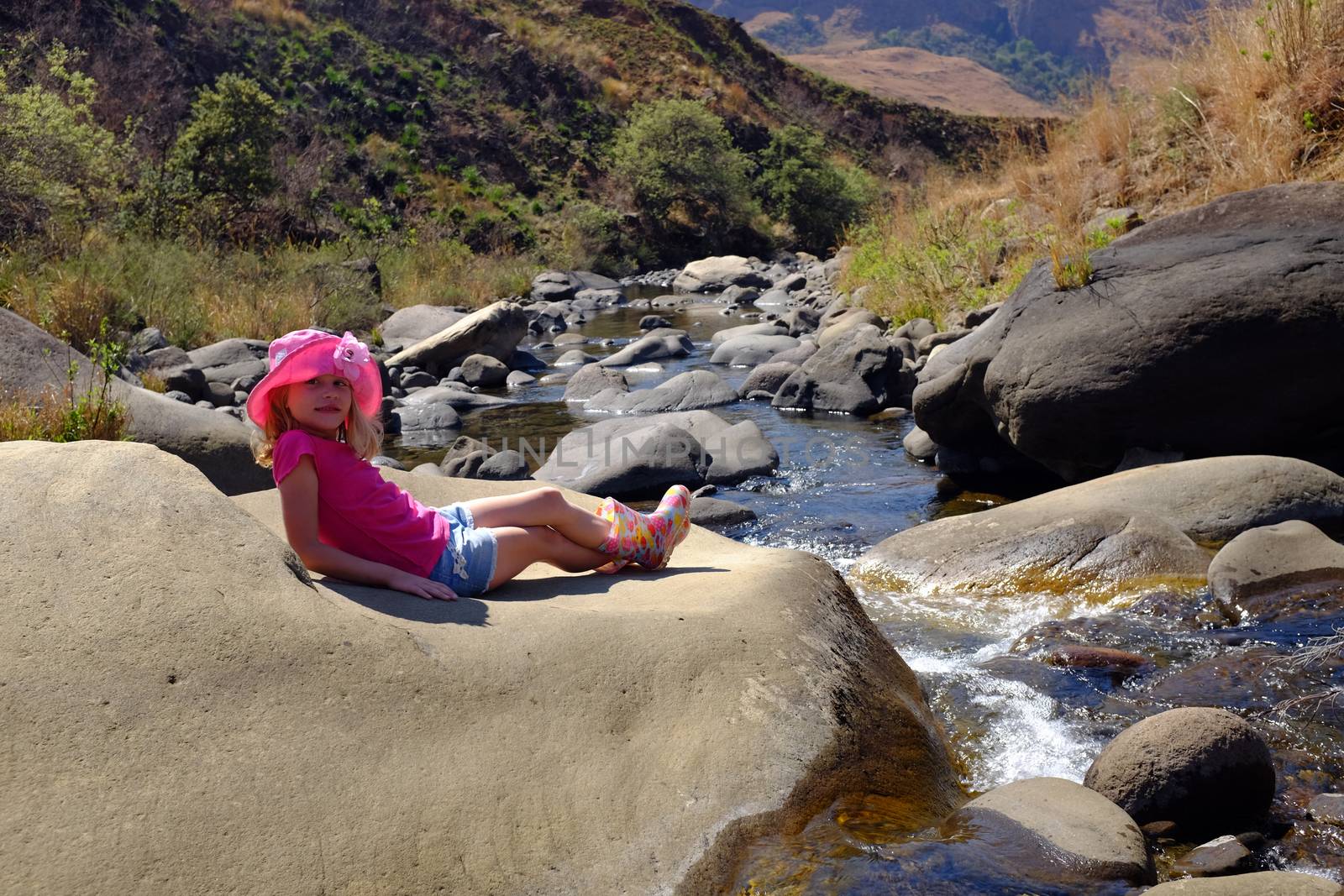Young child or girl on holiday relaxing at South African Drakensburg mountain stream or river