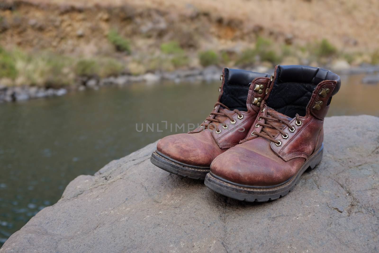 Pair of old hiking boots on rock at river or stream at Lotheni. KwaZulu-Natal in the South African Drakensburg mountains