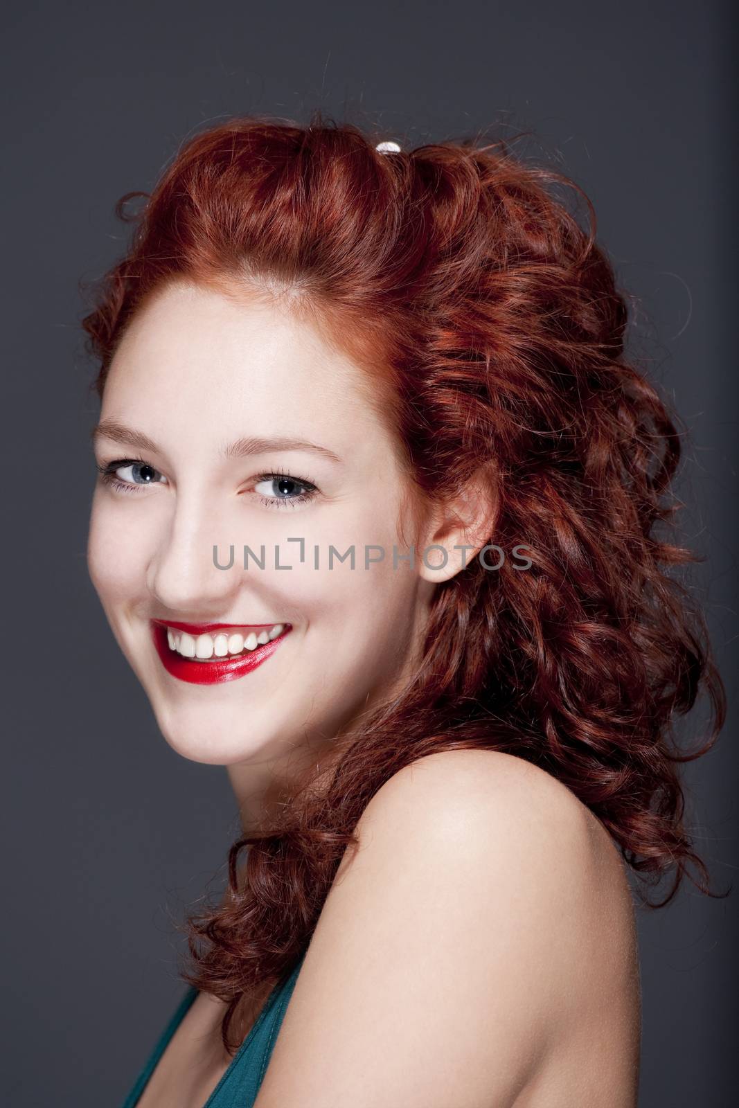 beautiful teenage woman with red hair smiling, looking - isolated on gray