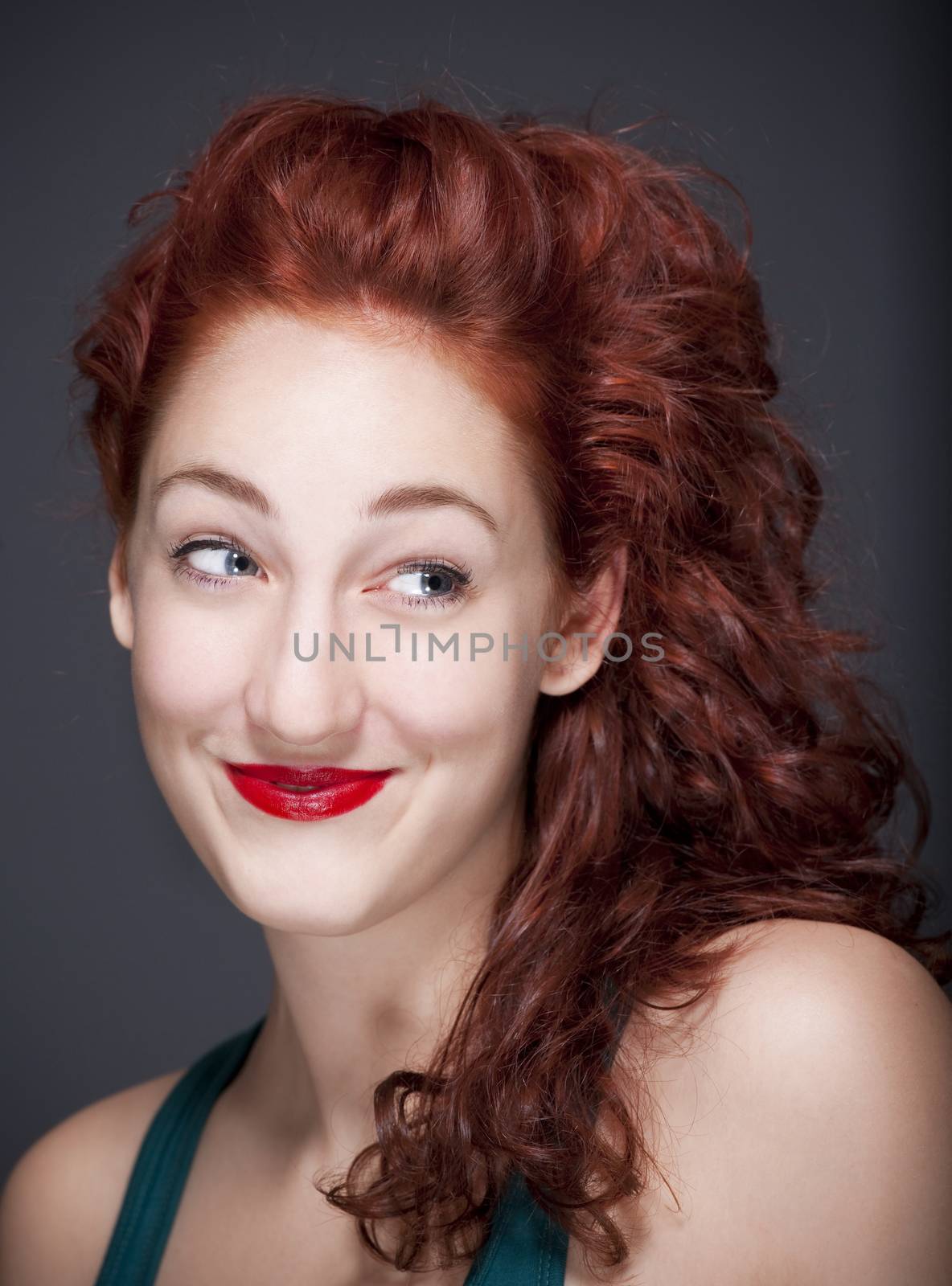 beautiful teenage woman with red hair smiling, looking - isolated on gray