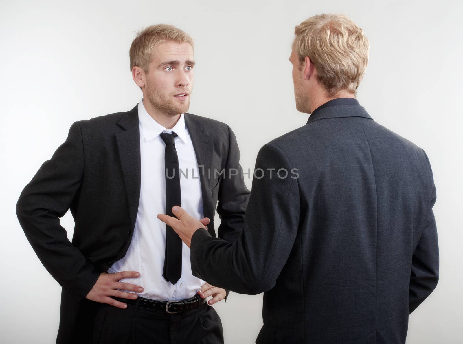 two you businessmen standing, discussing, arguing - isolated on light gray